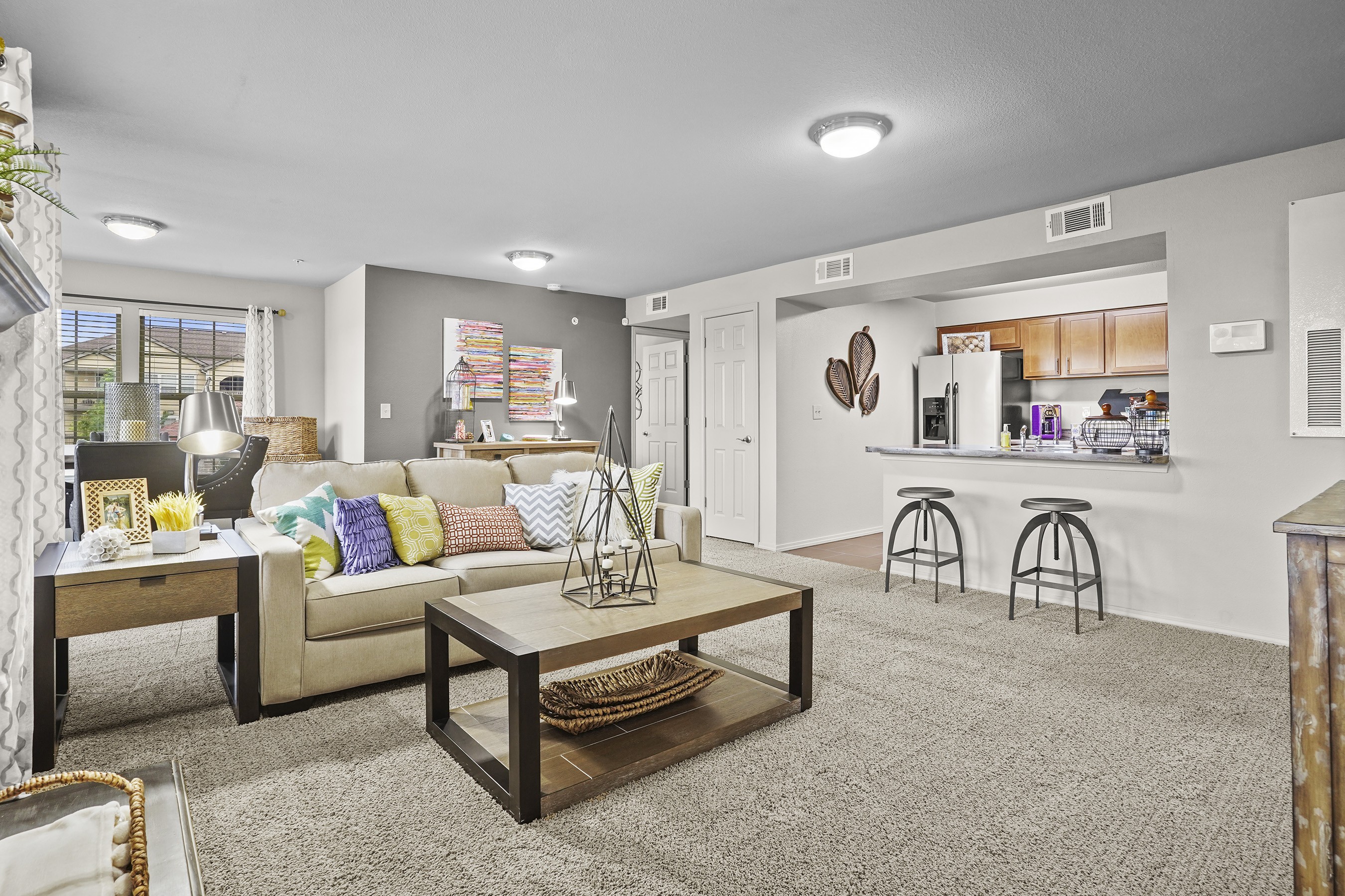 A living room with a couch, coffee table, and bar stools.