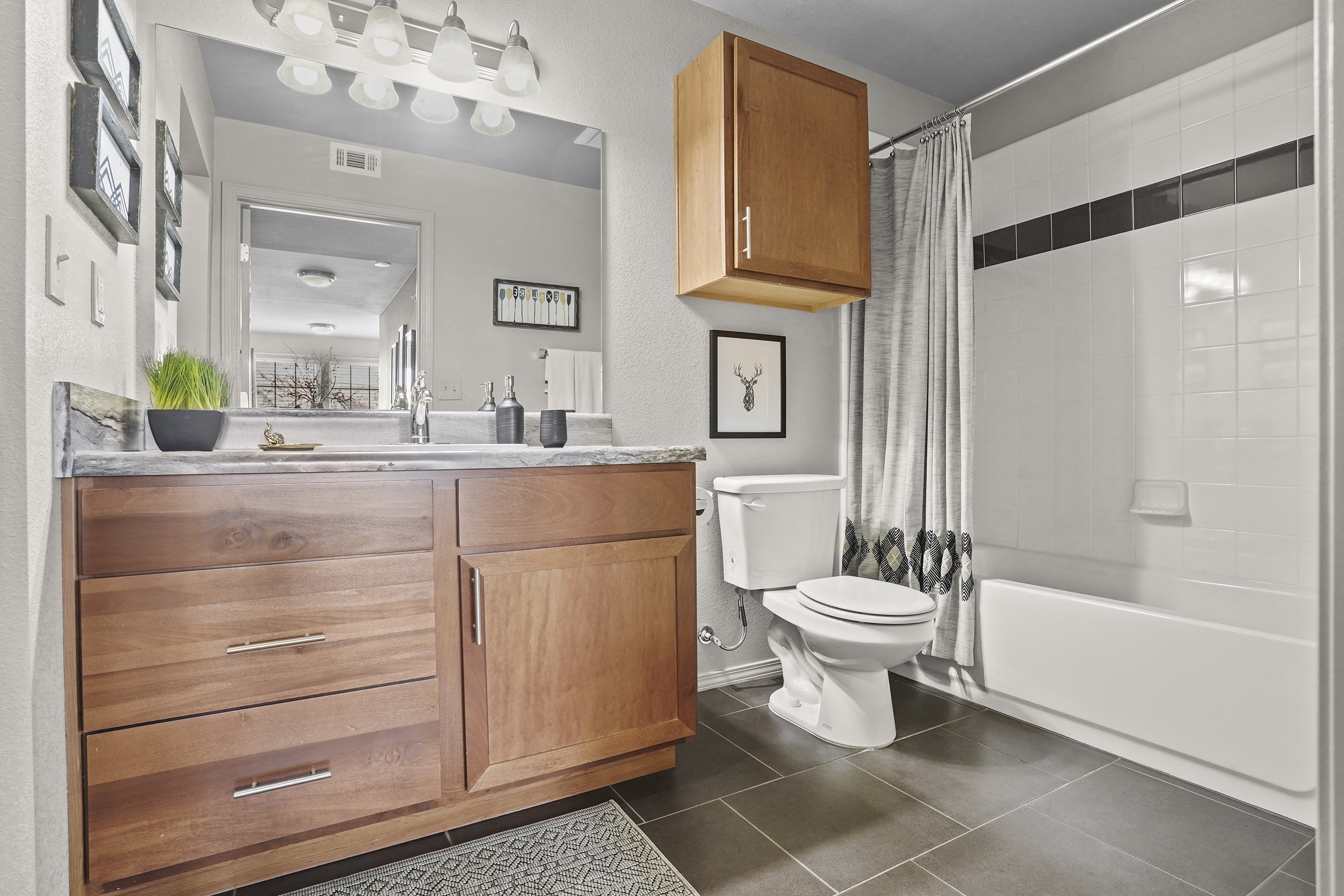 A modern bathroom with a wooden vanity and white fixtures.
