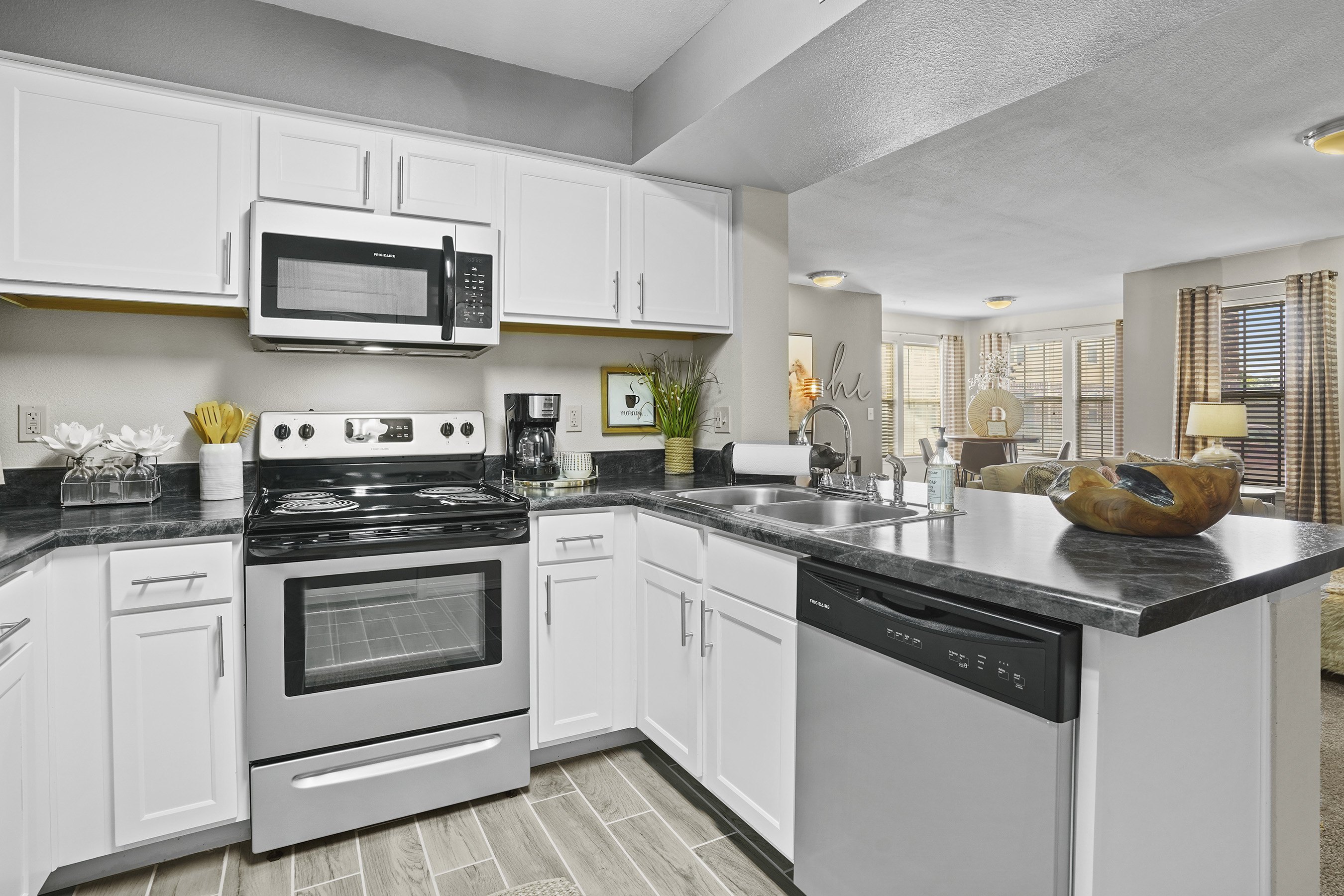 A modern kitchen with white cabinets and black countertops.