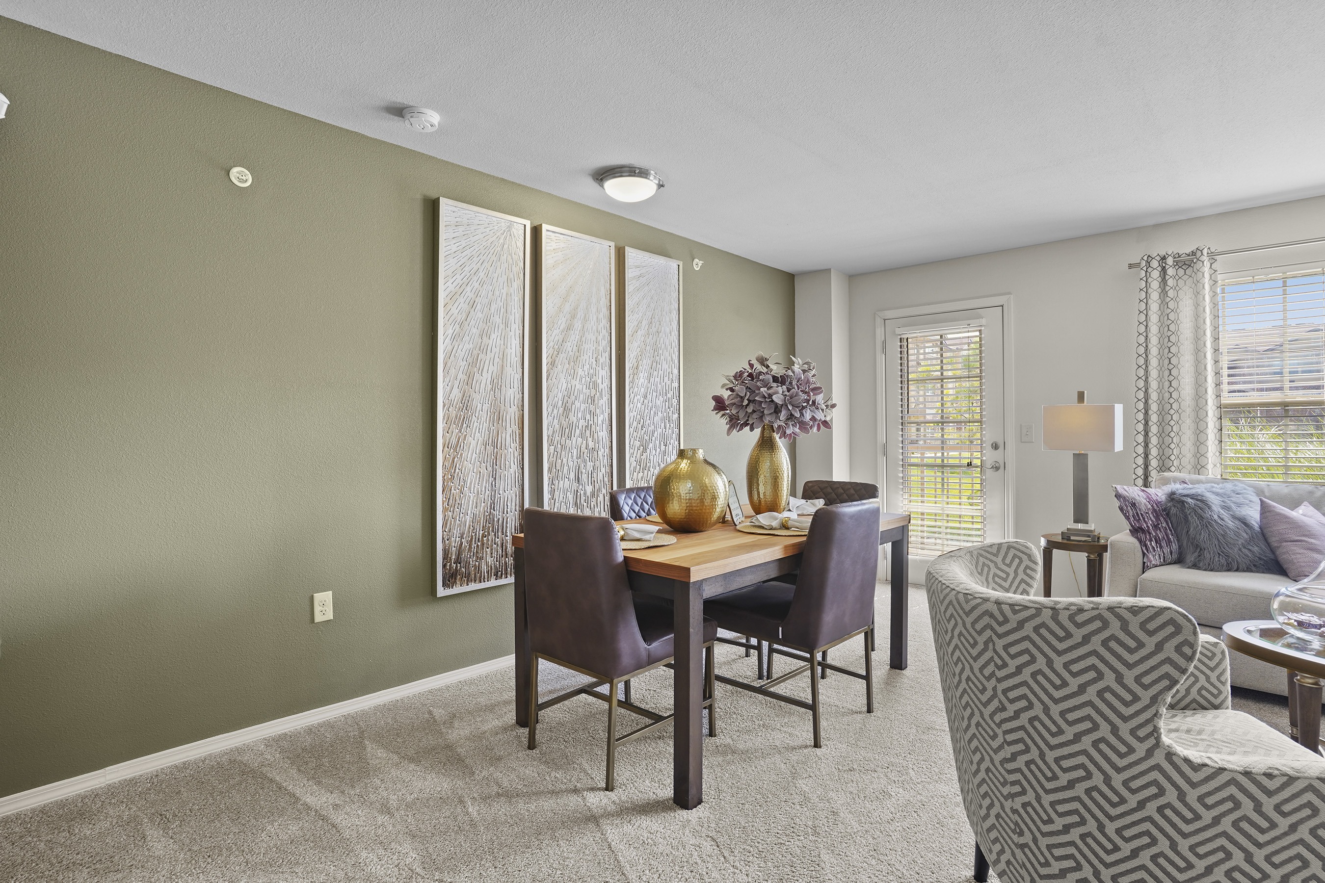 A dining room with a table set for two and a couch with a pillow.