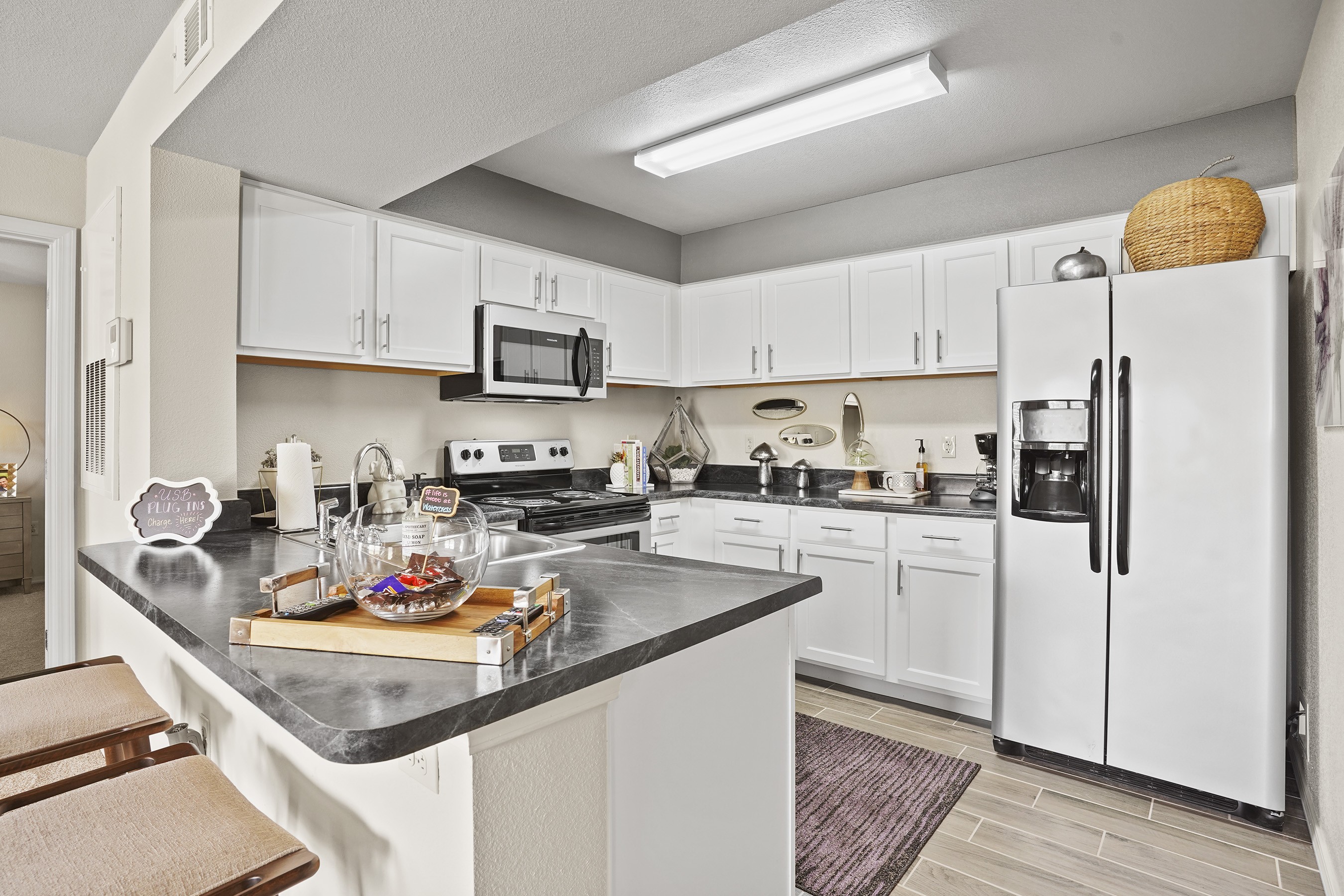 A kitchen with white cabinets and a black counter top.