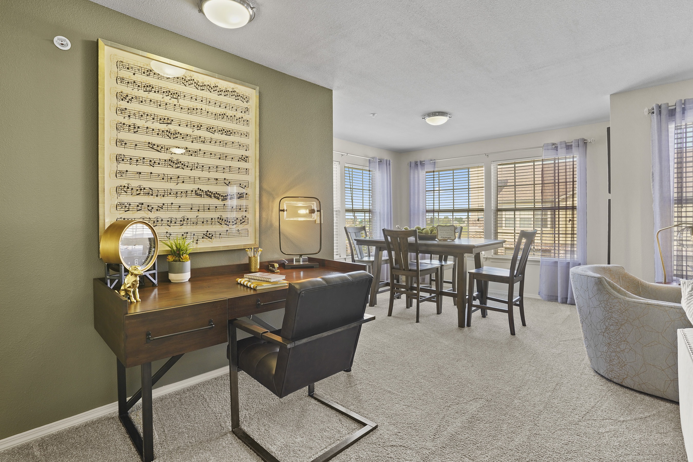 A room with a desk, chairs, and a large window.