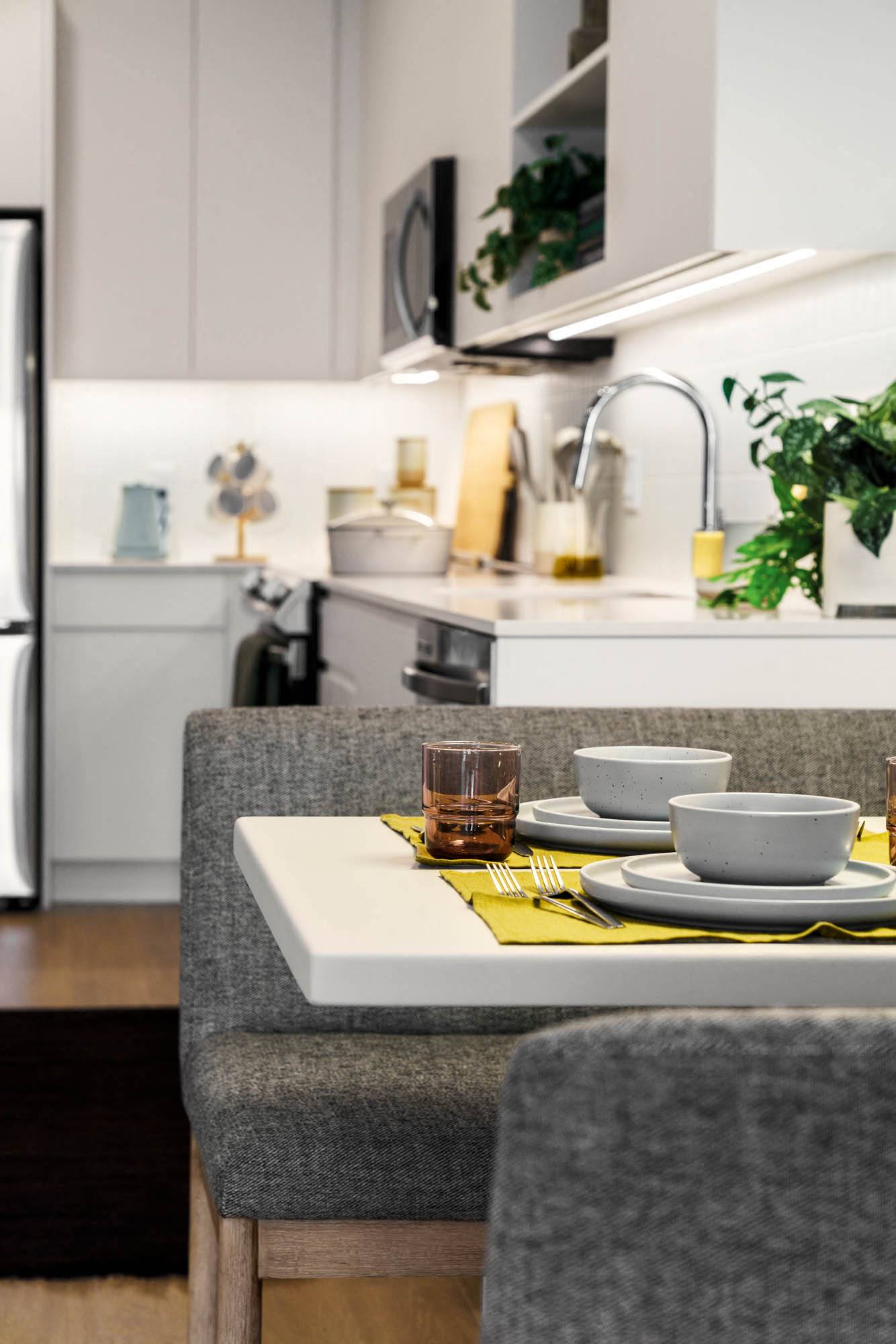an open kitchen and dining area with a table and chairs,,a rendering of a living room with a table and chairs,a white kitchen with a white island and a stainless steel refrigerator,