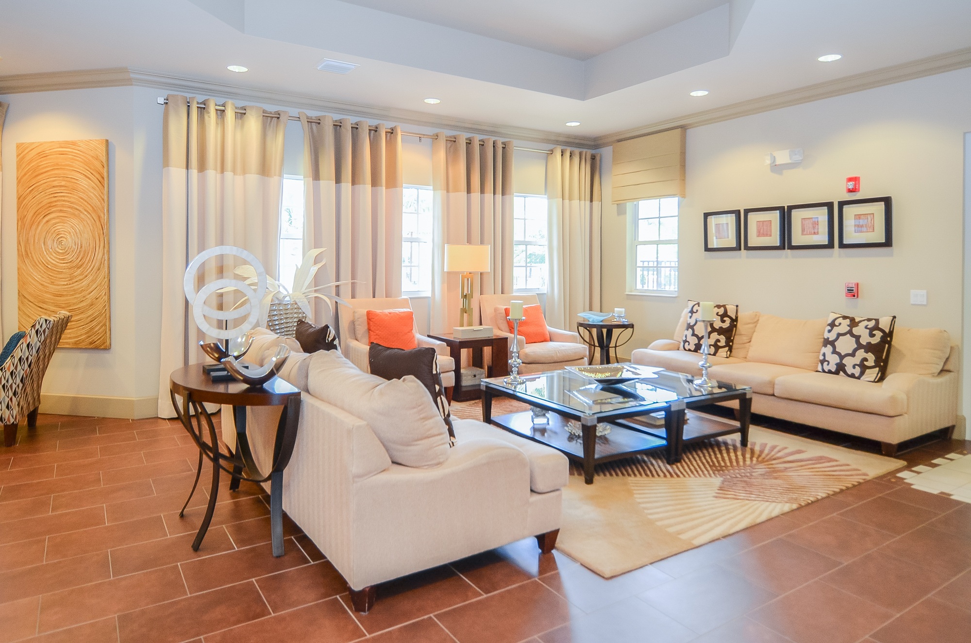A living room with a white sofa, a coffee table, and a glass table with a vase on it.