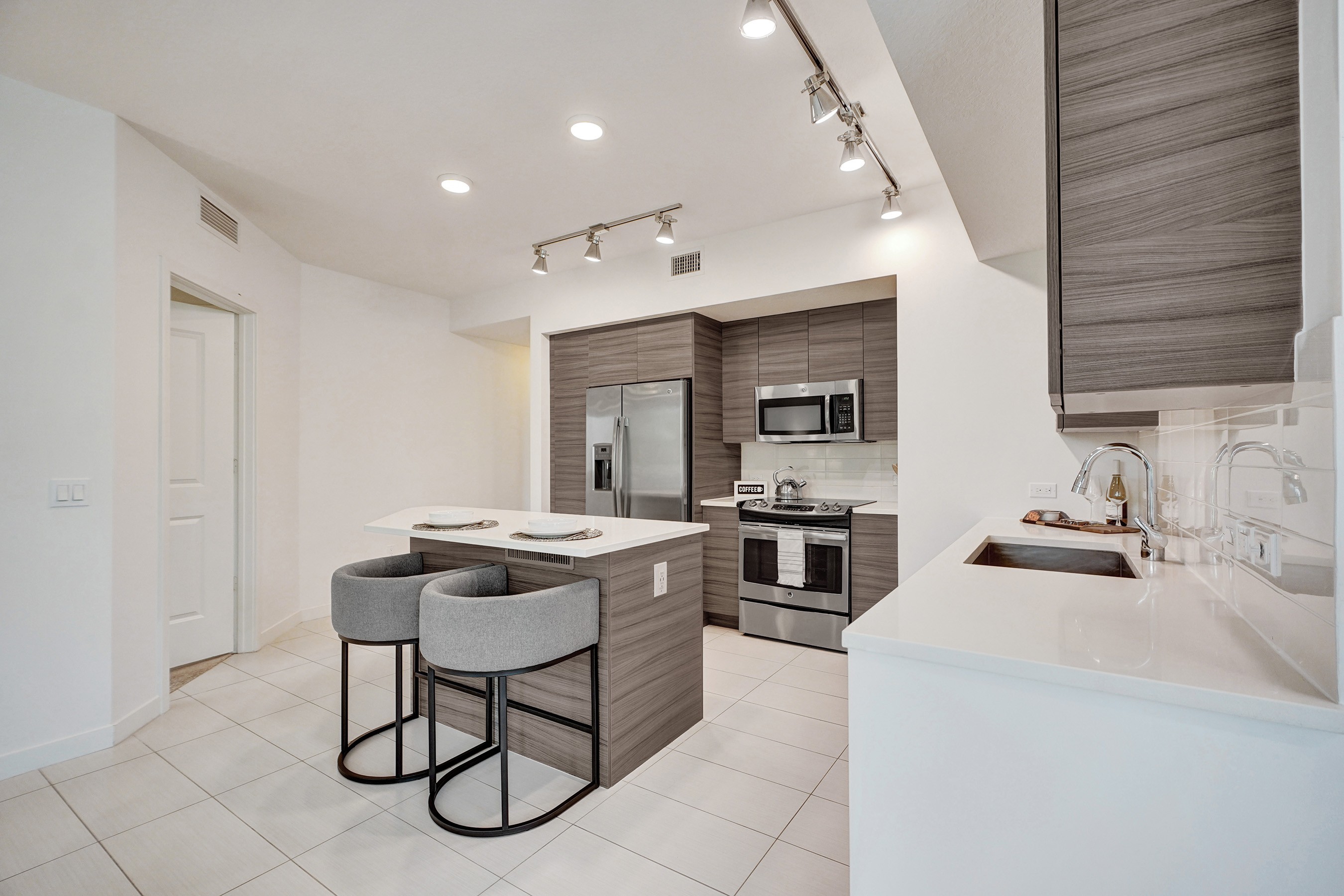 A modern kitchen with a bar area and a microwave above the stove.