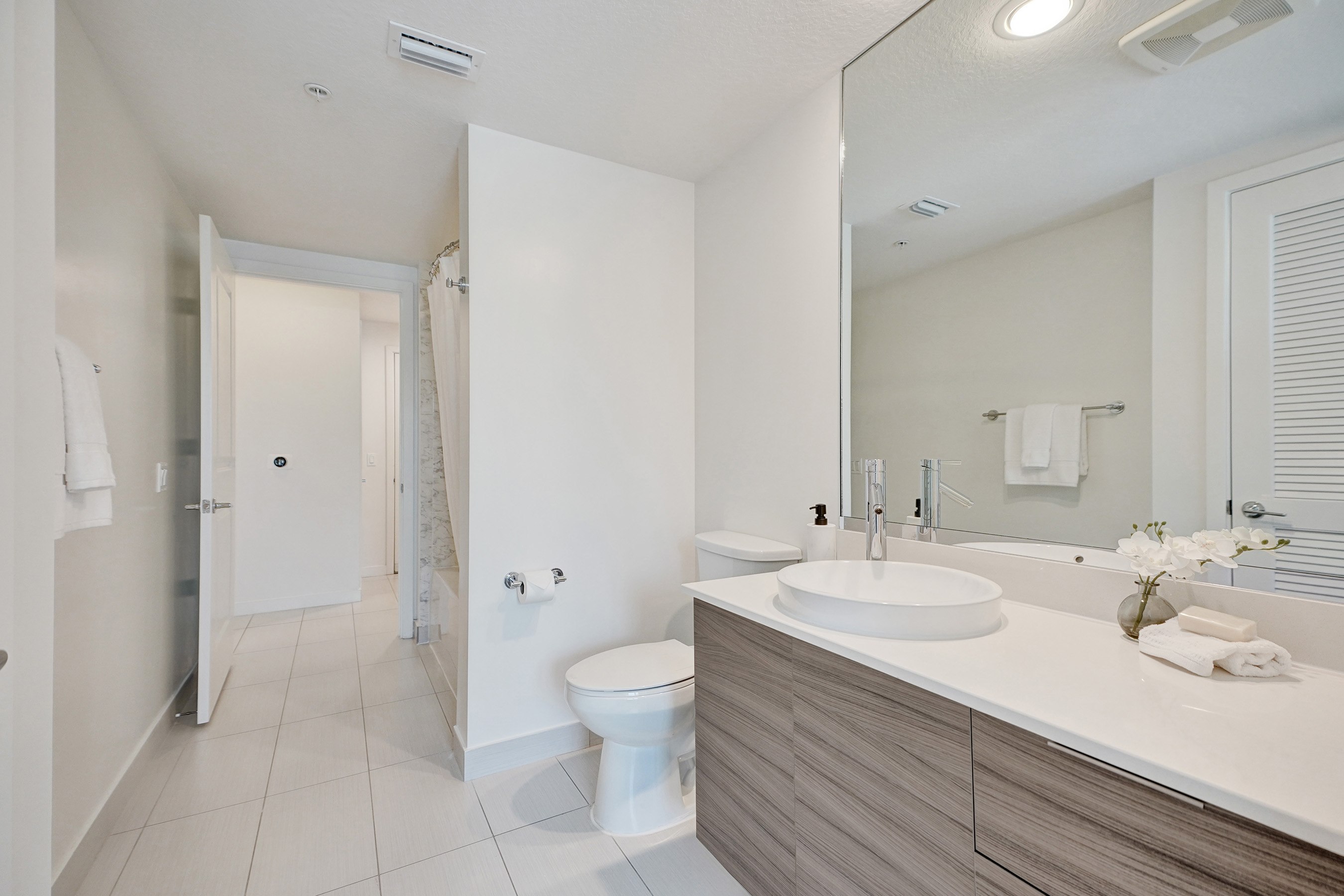 A white bathroom with a toilet, sink, and mirror.