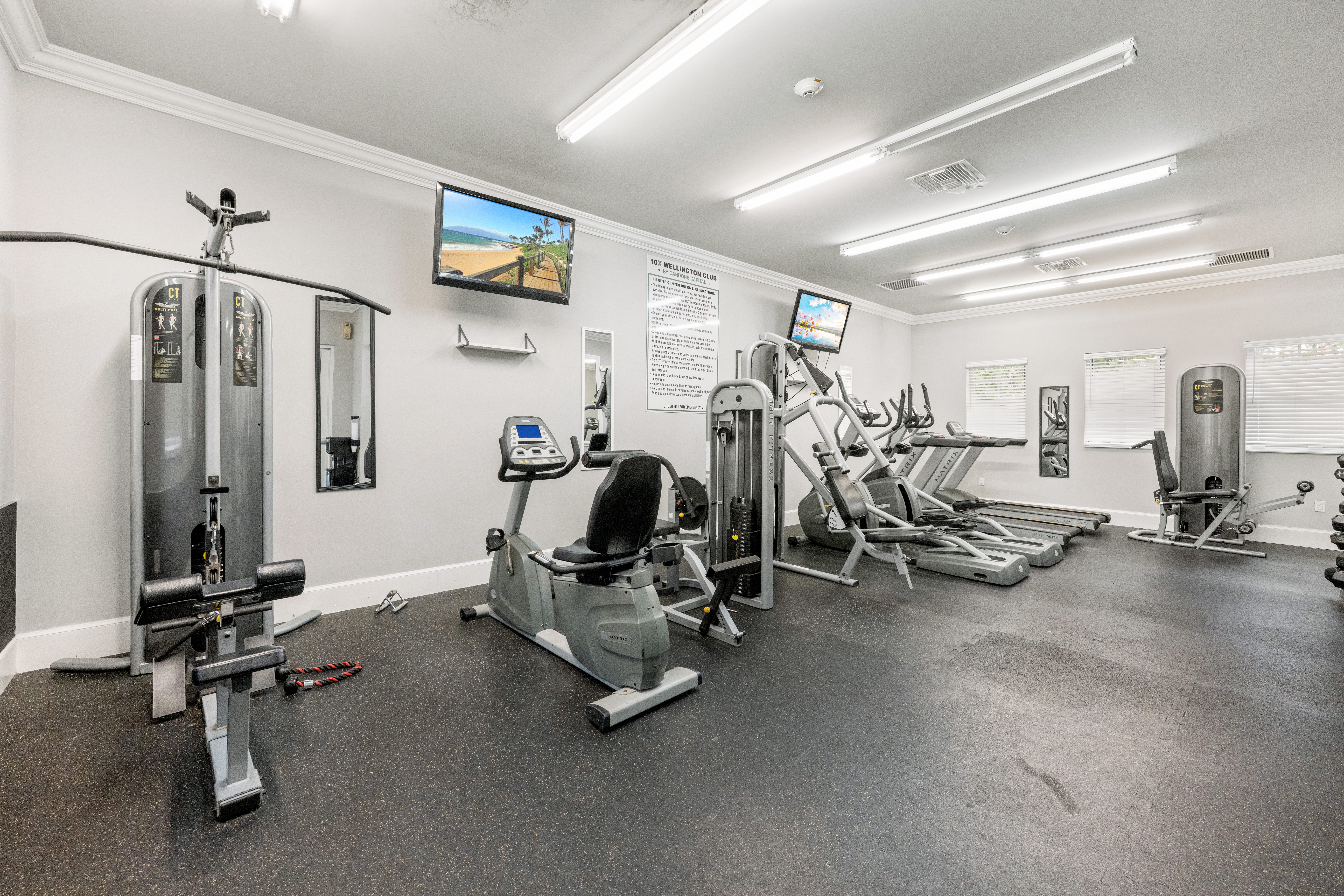 A gym with a variety of equipment including treadmills, weights, and exercise machines.