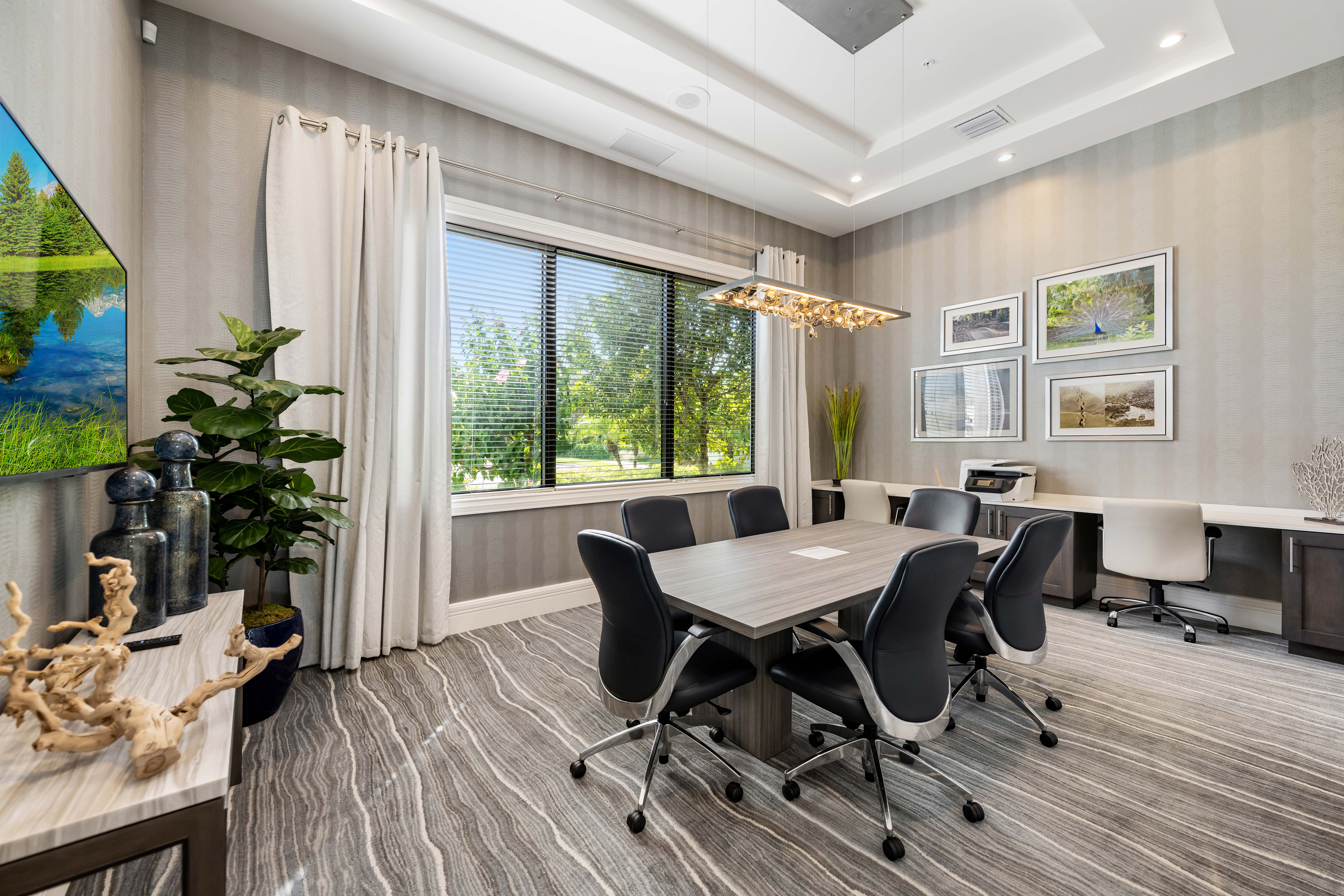 A conference room with a long table and chairs, a plant, and pictures on the wall.