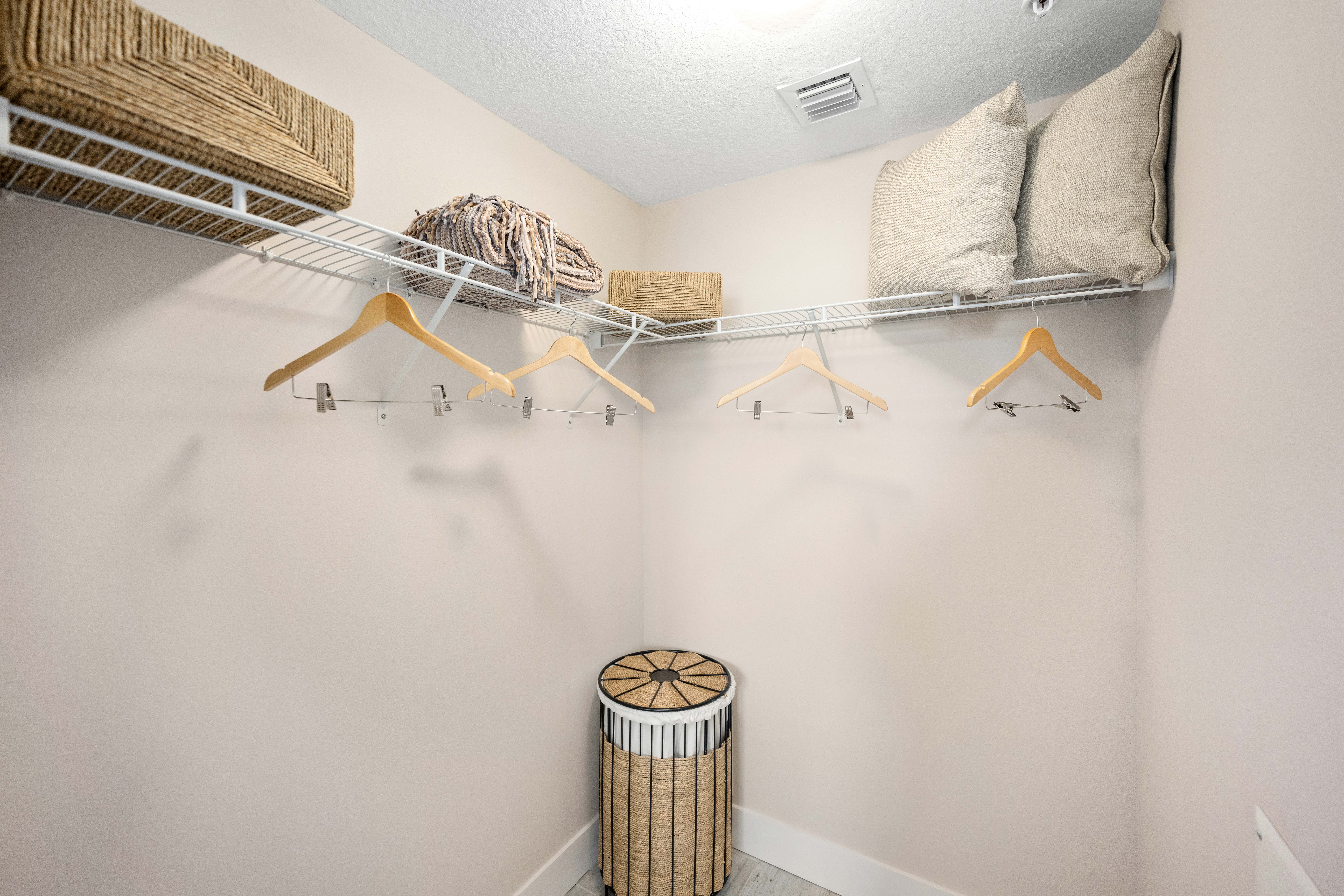 A white closet with a shelf and a trash can.