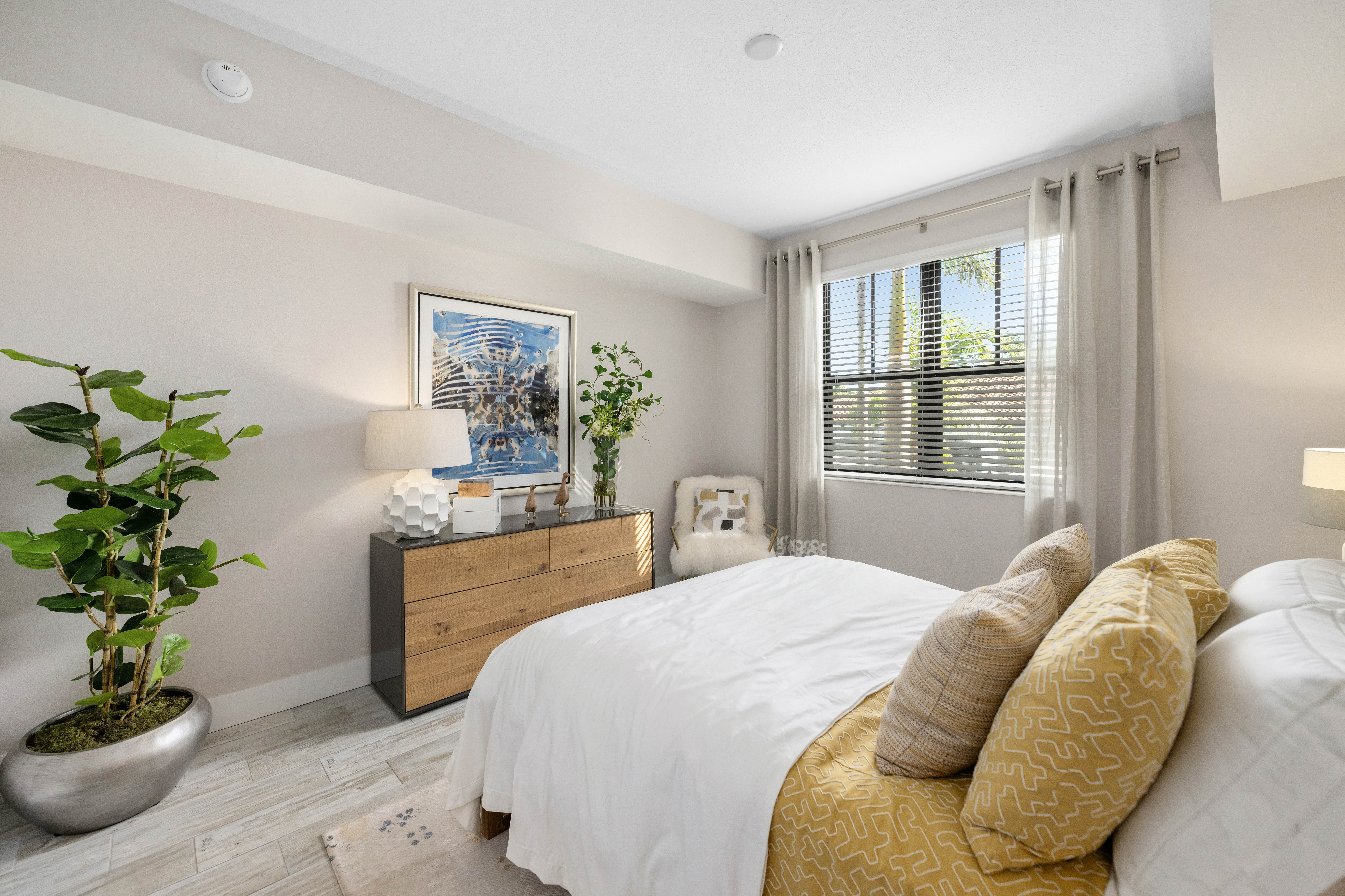 A bedroom with a bed, nightstand, and a potted plant.