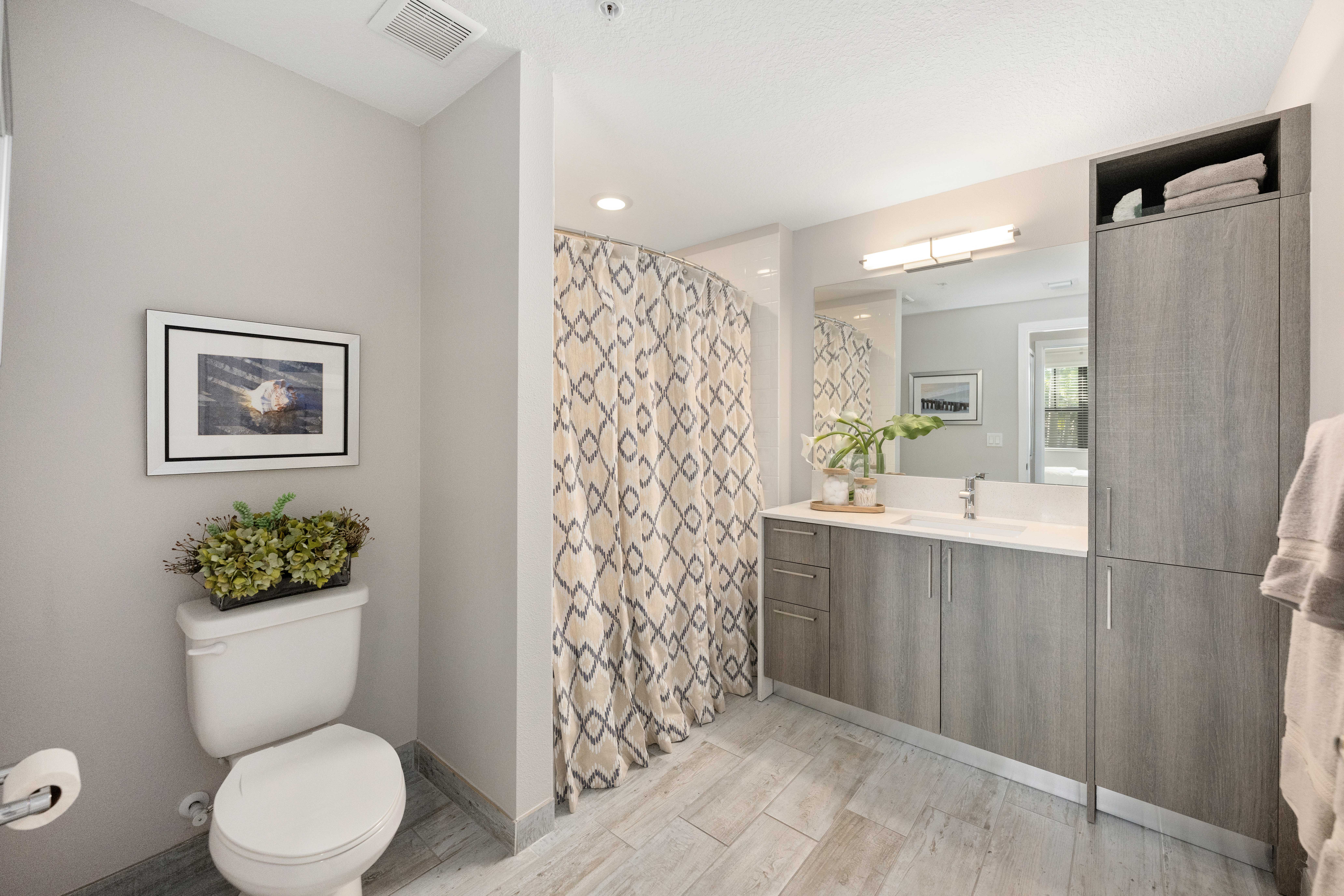 A bathroom with a toilet, sink, and a potted plant.