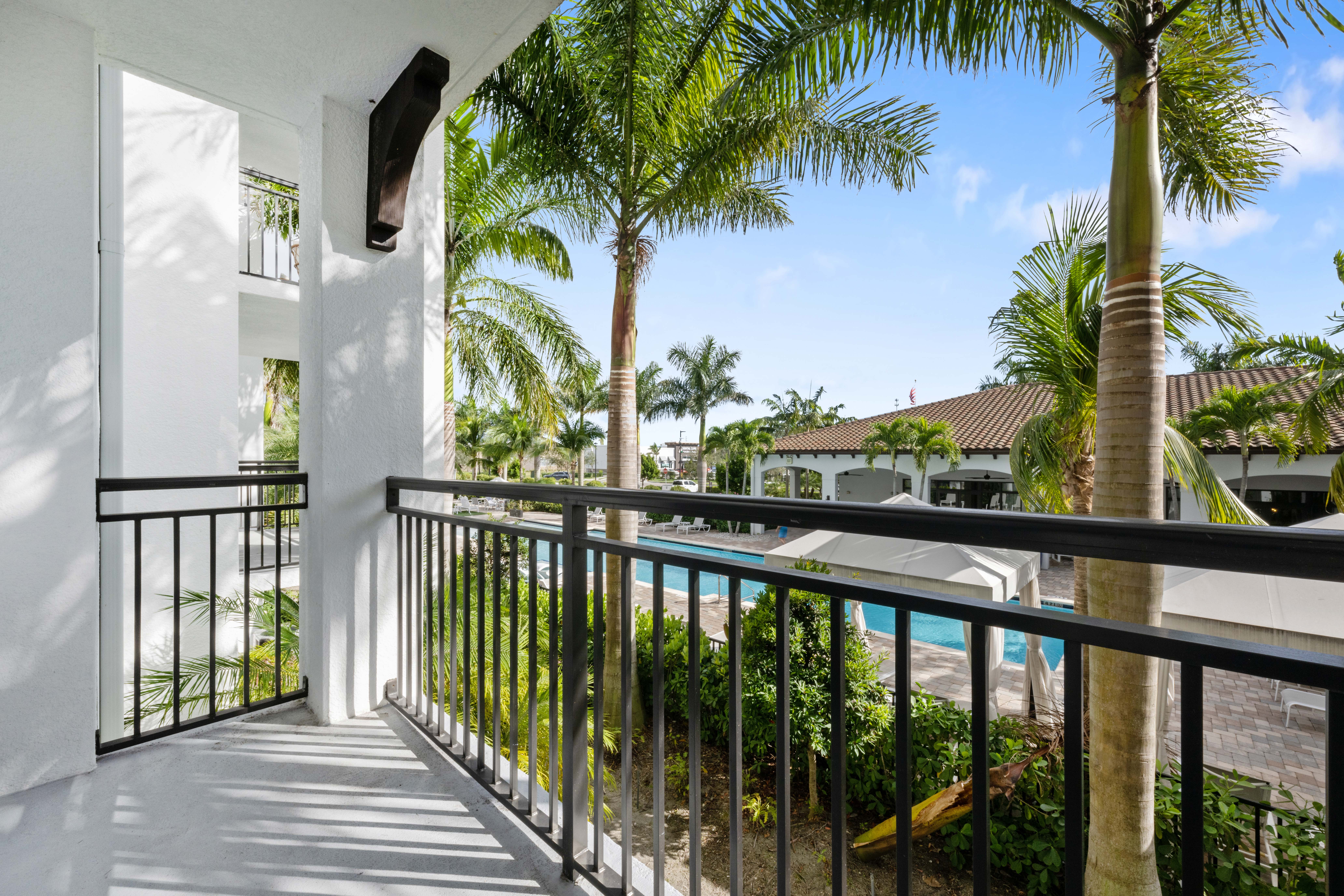 A balcony with a black railing and a pool in the background.
