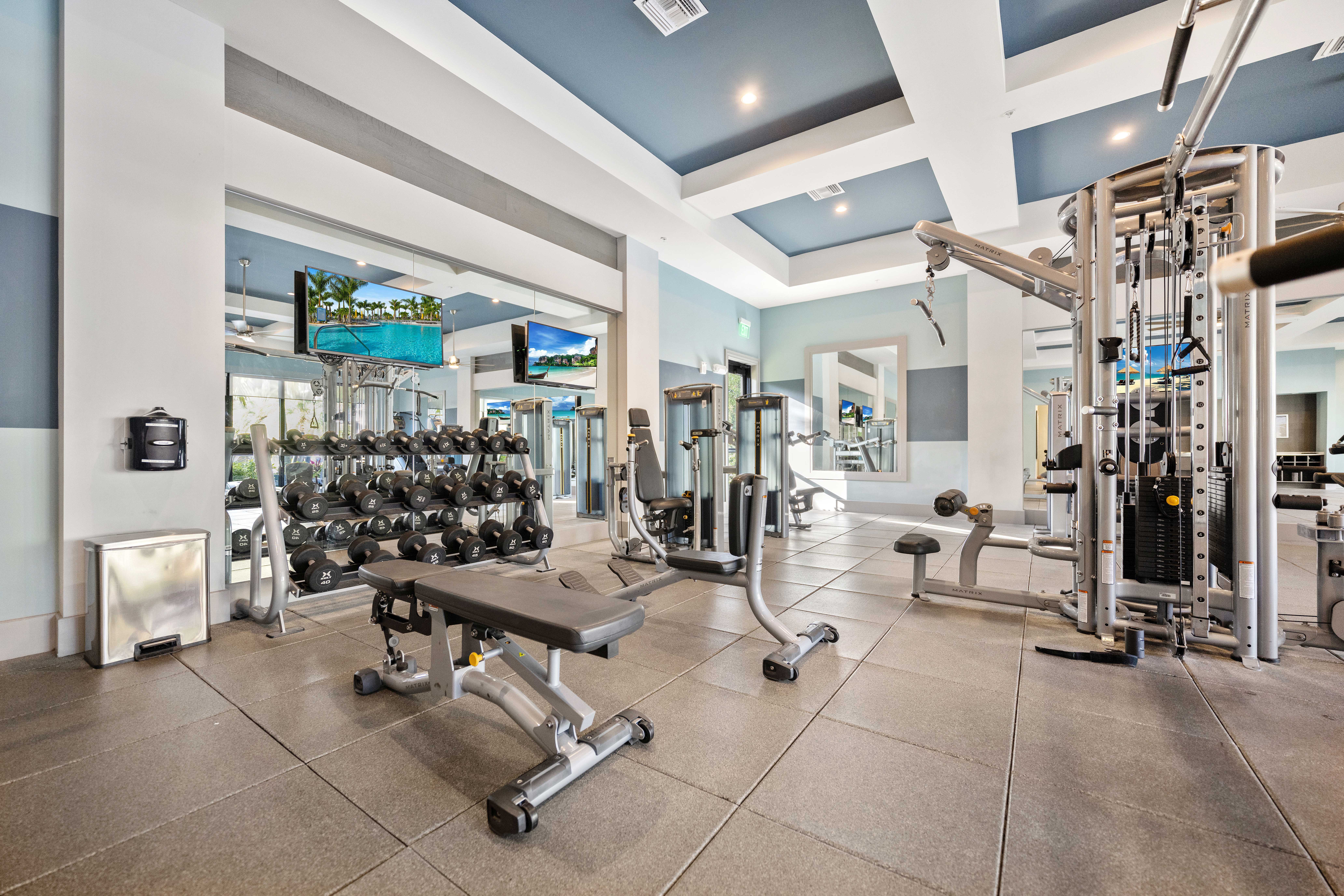 A gym with a variety of equipment including dumbbells, weight machines, and a bench.