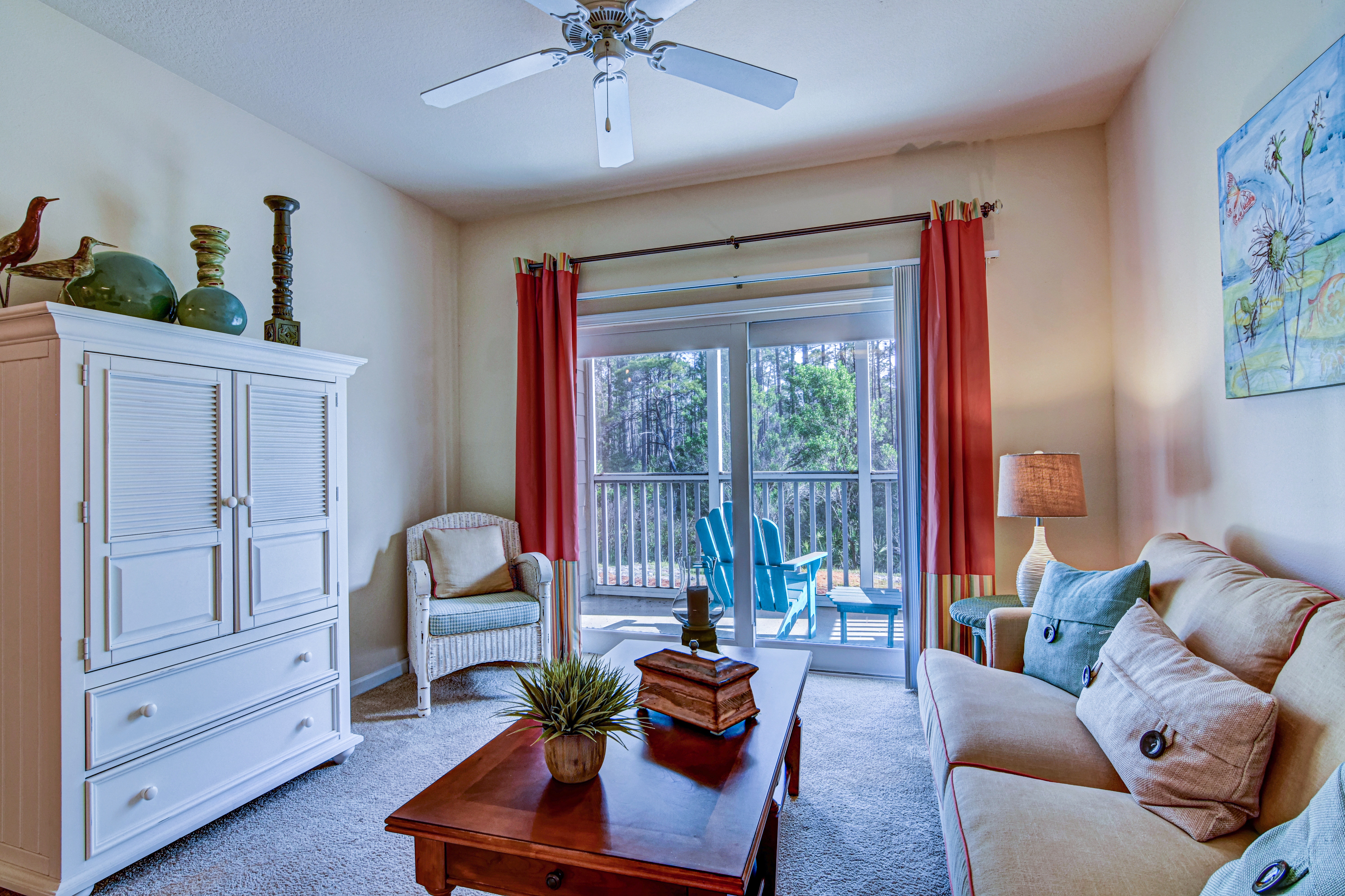 A living room with a white dresser, a wooden coffee table, a white couch, and a painting on the wall.