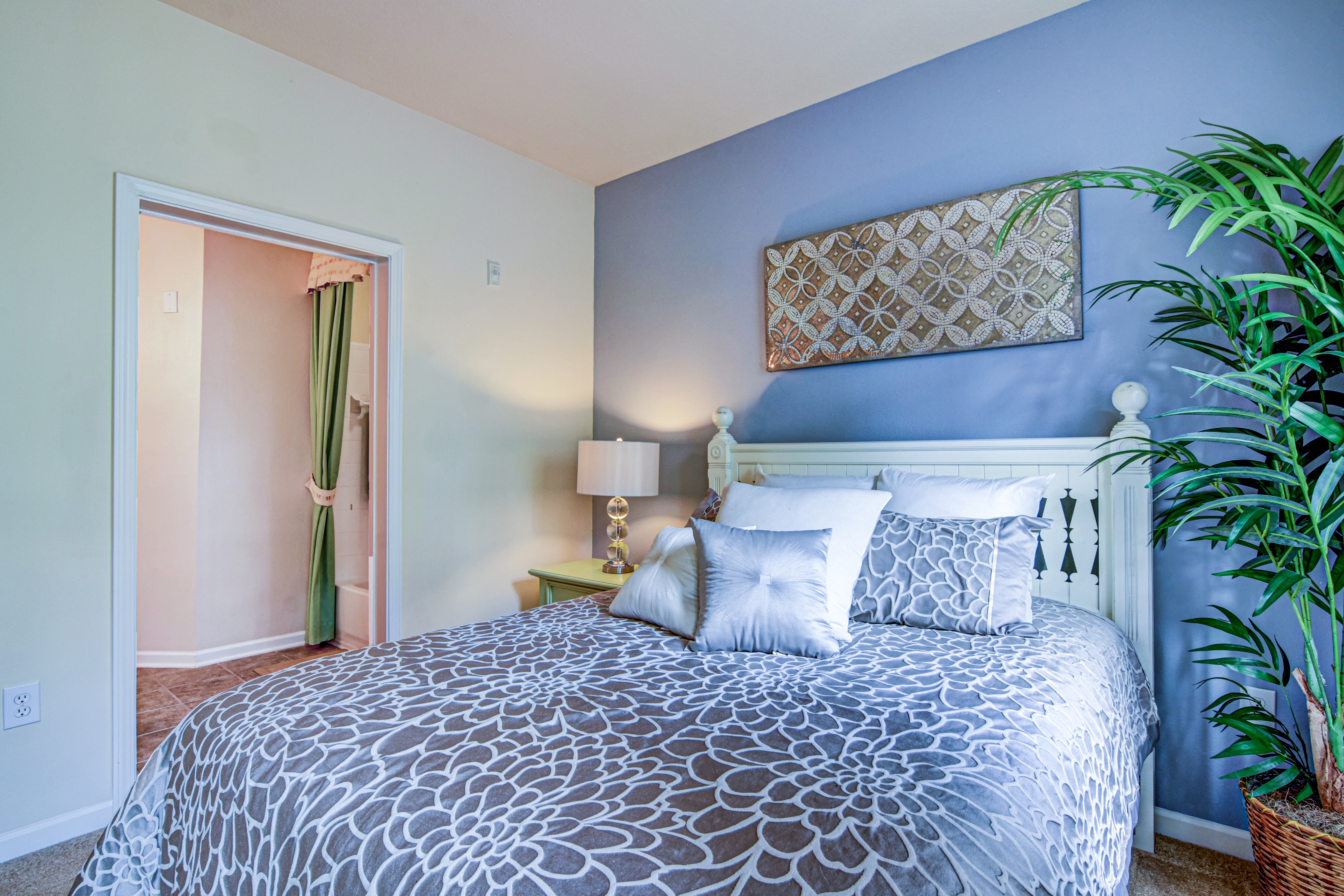 A bedroom with a patterned bedspread and a white bed.
