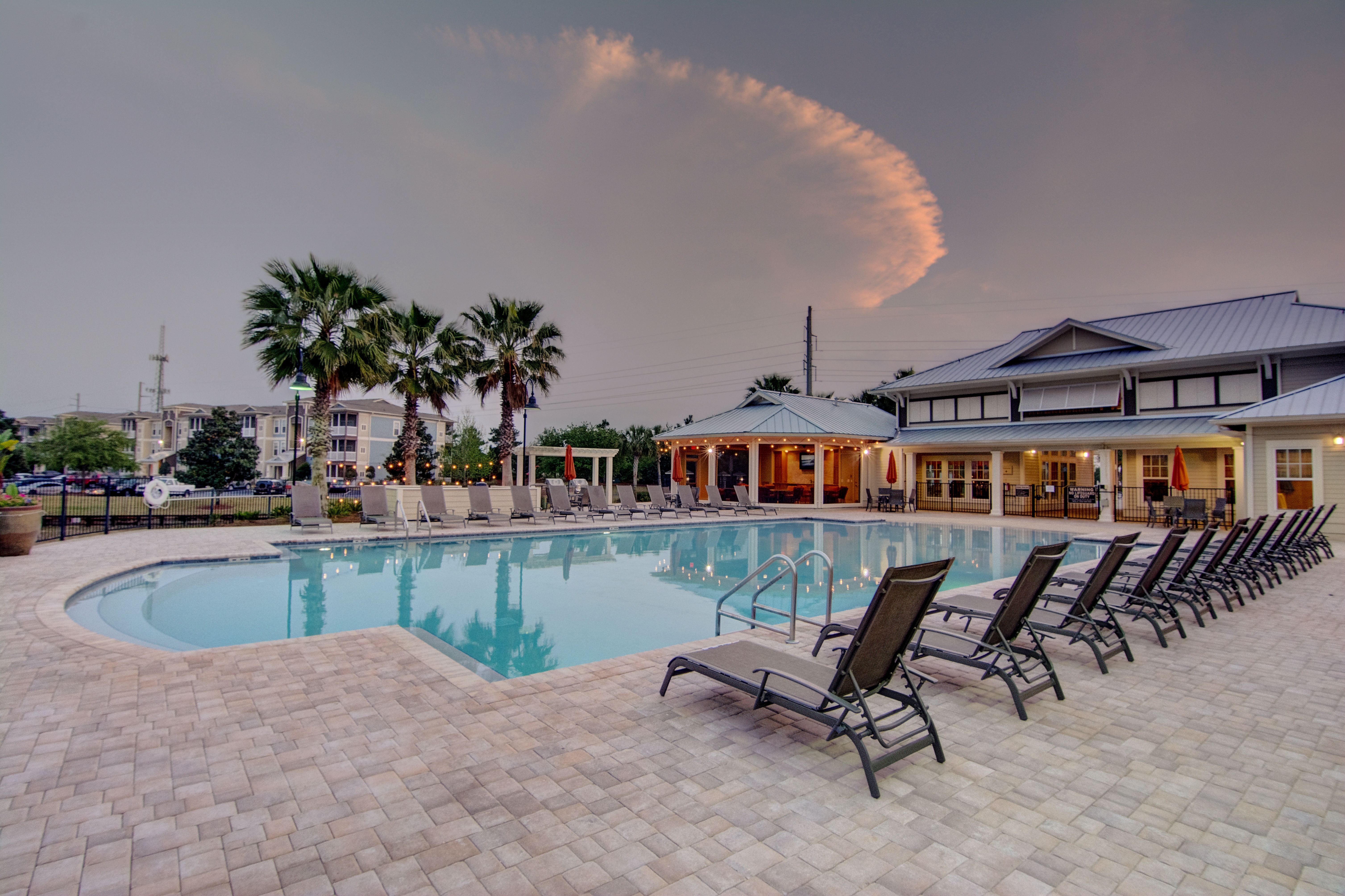 A swimming pool surrounded by lounge chairs and palm trees.