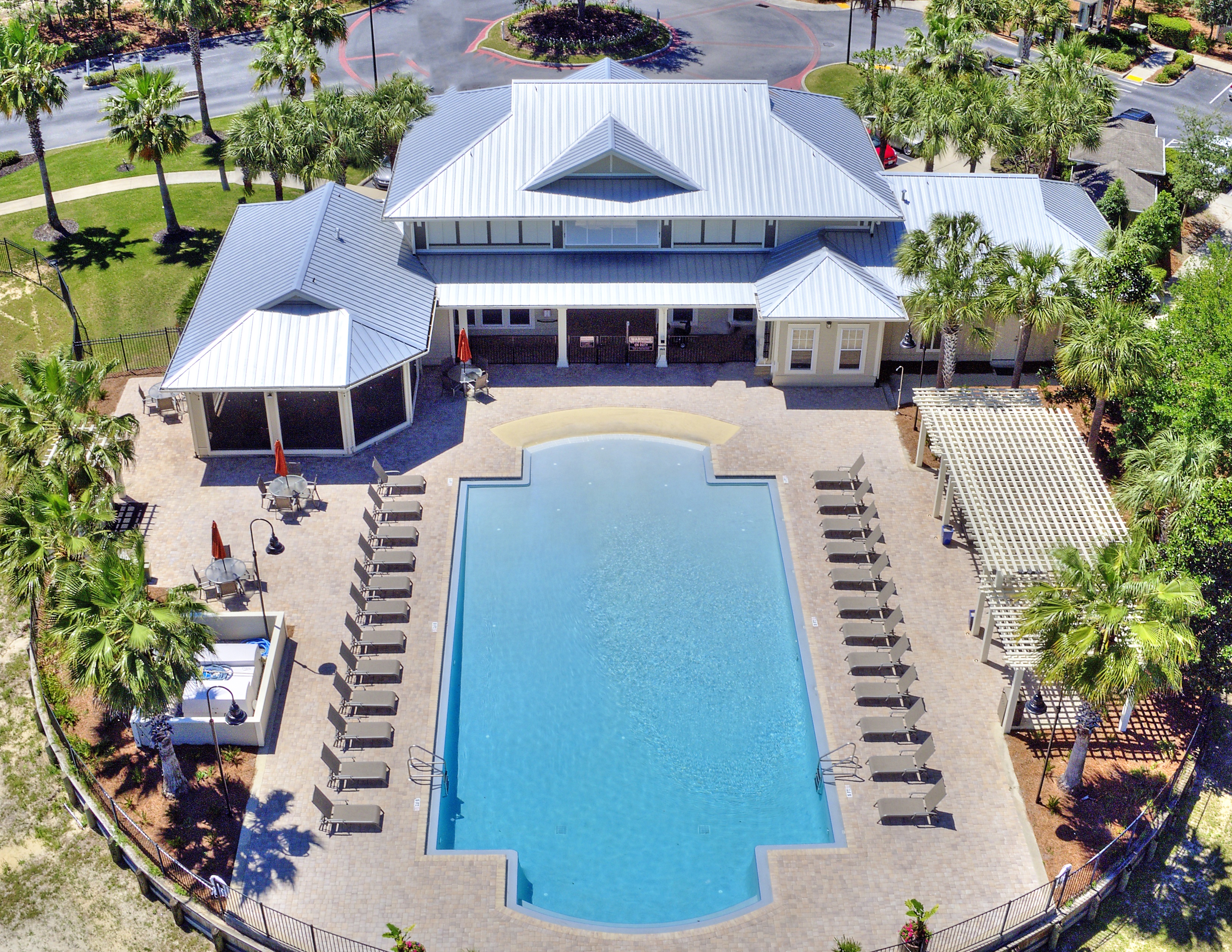A large swimming pool surrounded by a metal fence and lounge chairs.