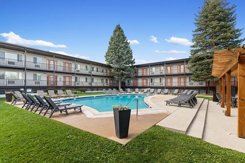 A pool surrounded by chairs and trees in a courtyard.