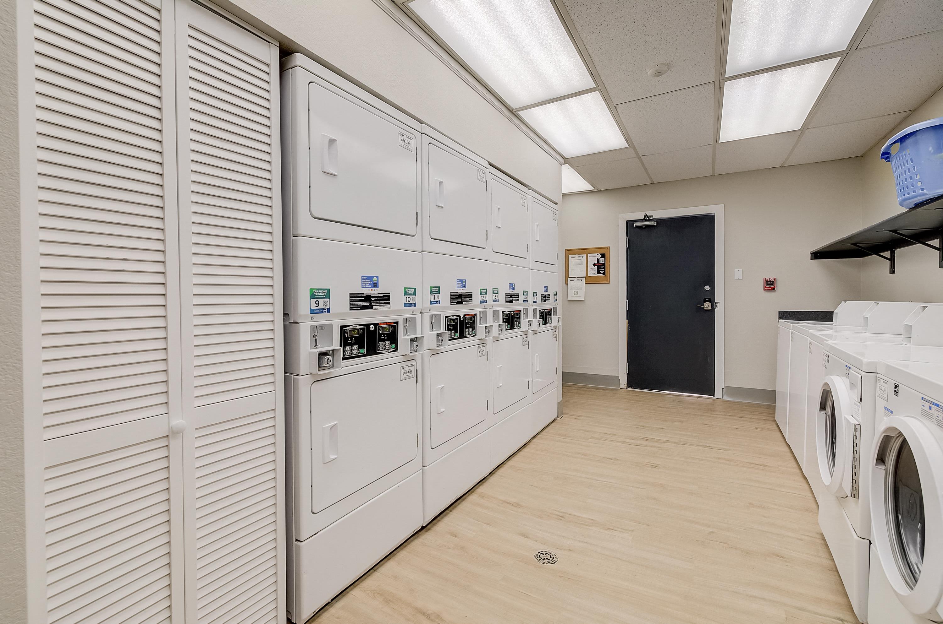 a laundry room with white washers and dryers and a black door