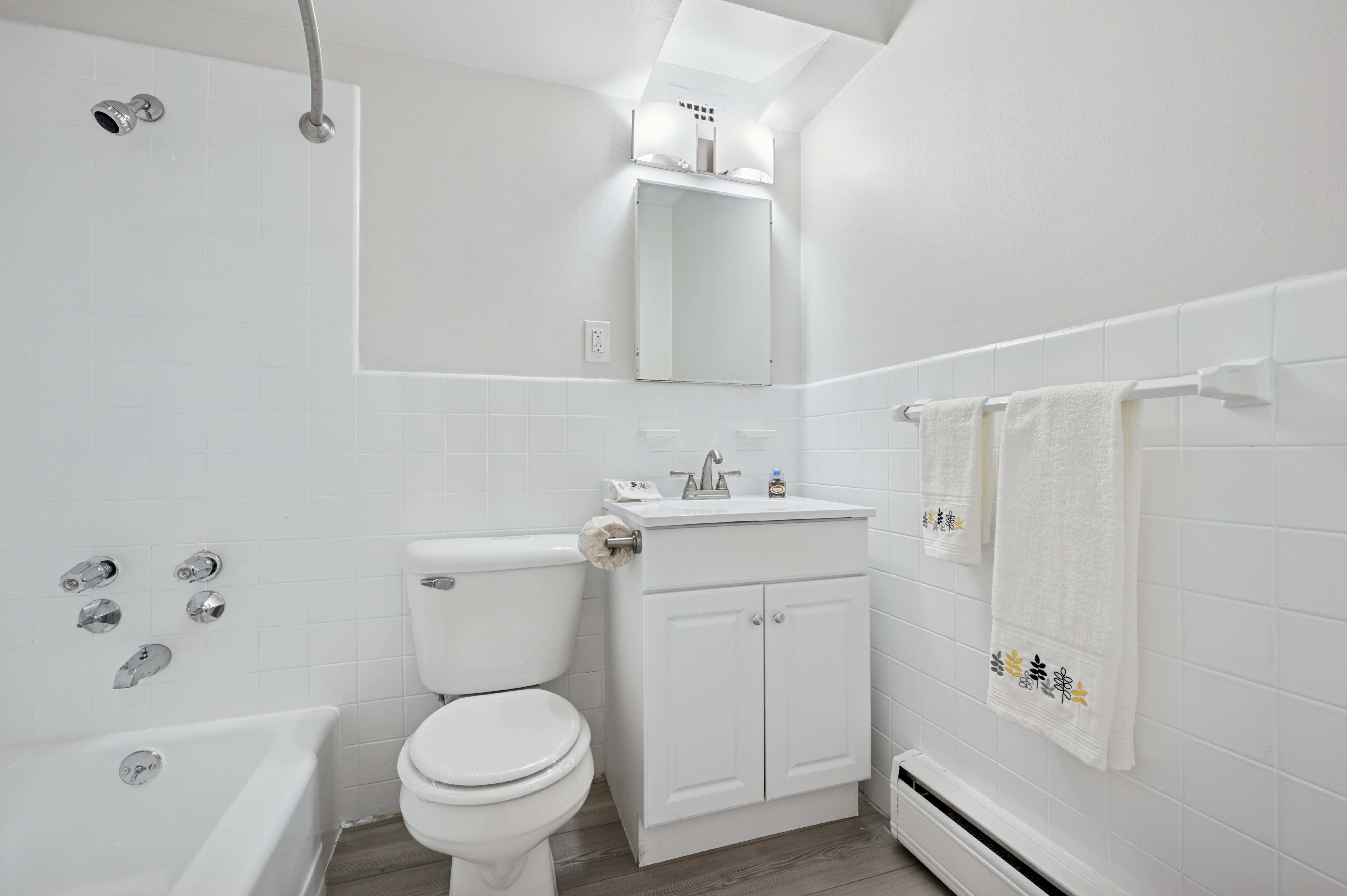 A white bathroom with a toilet, sink, and shower.