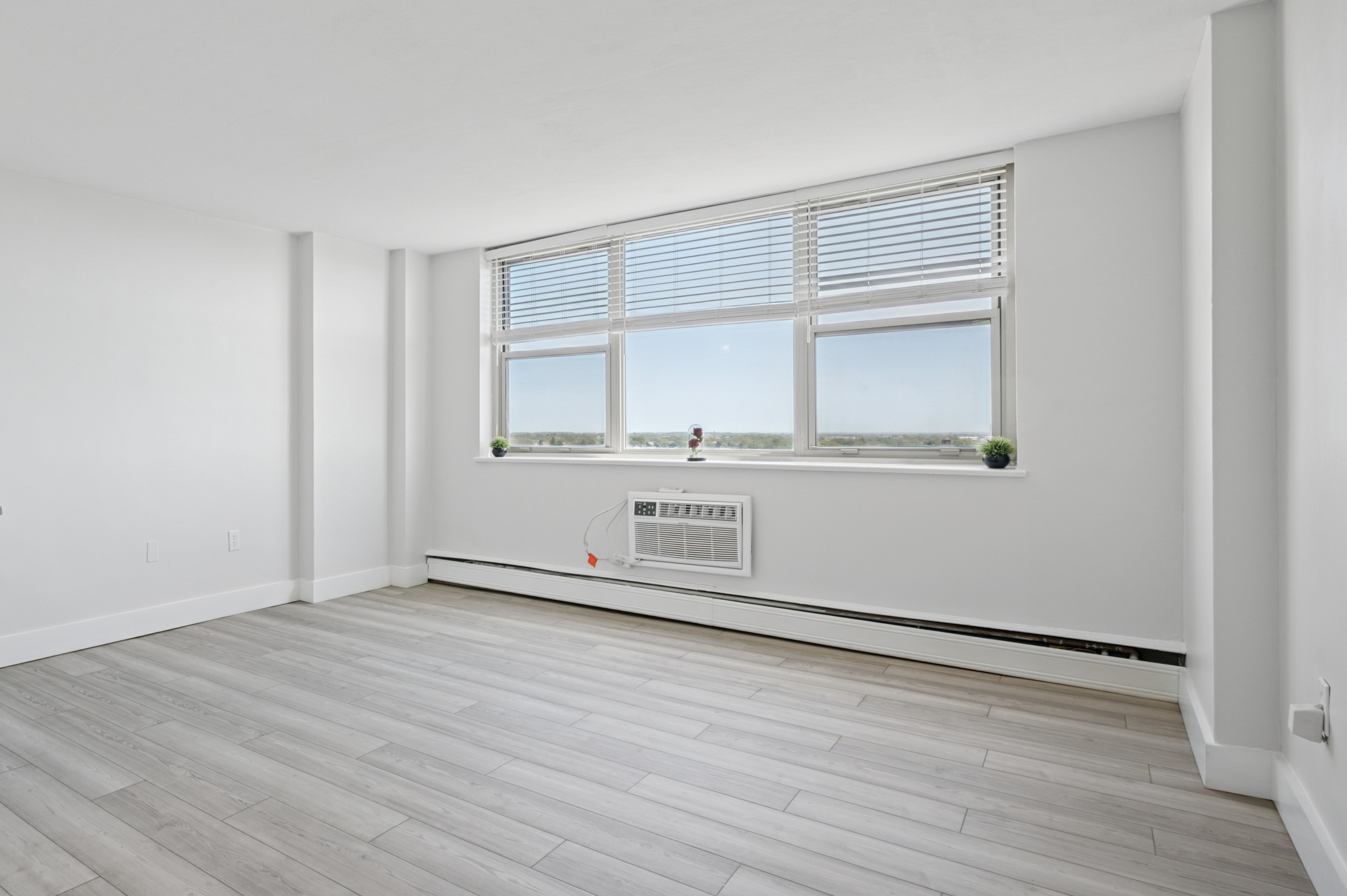 A room with a window and a wall-mounted air conditioner.
