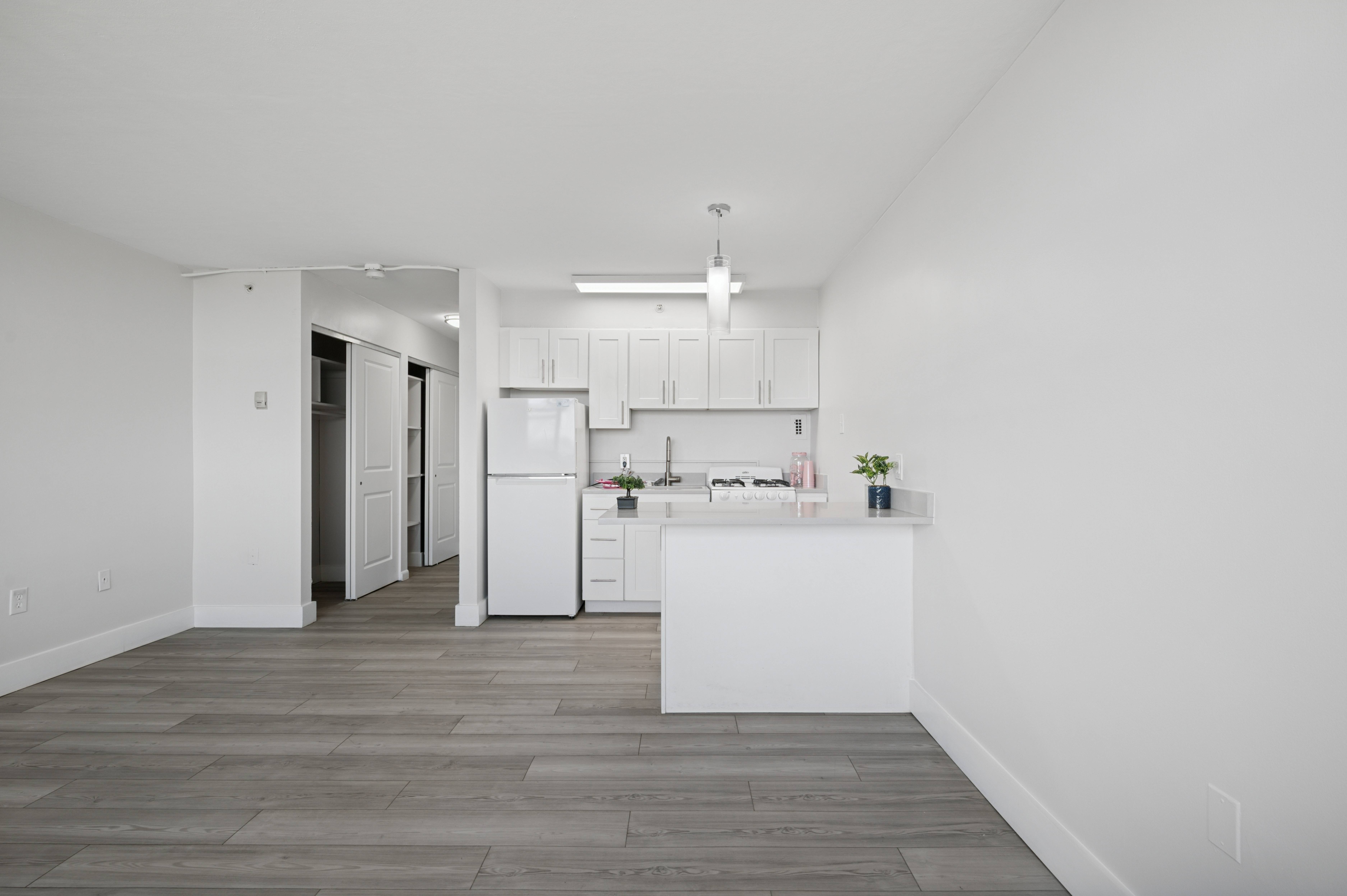 A kitchen with white cabinets and a white refrigerator.