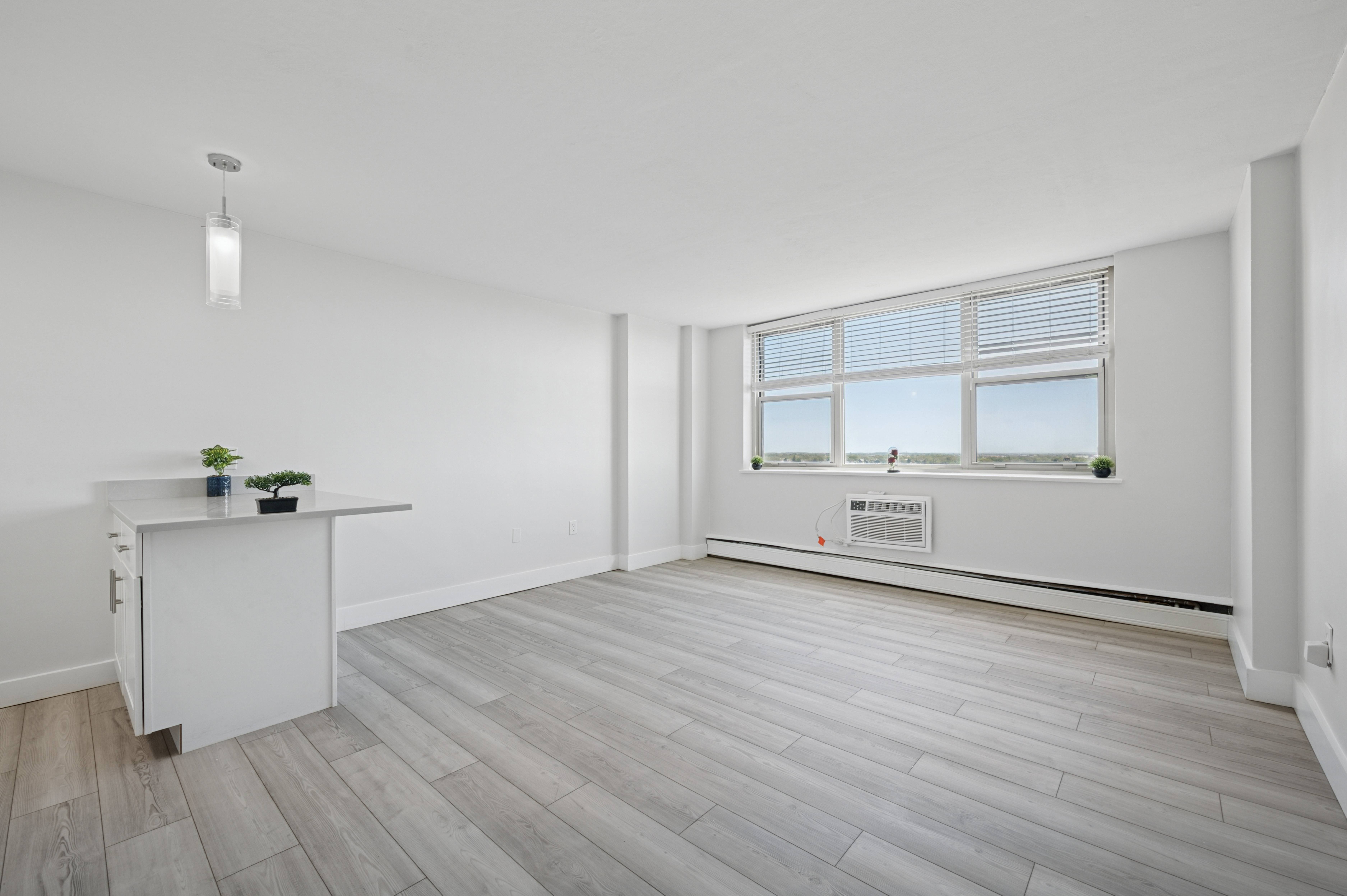 A room with a window and a desk with a plant on it.