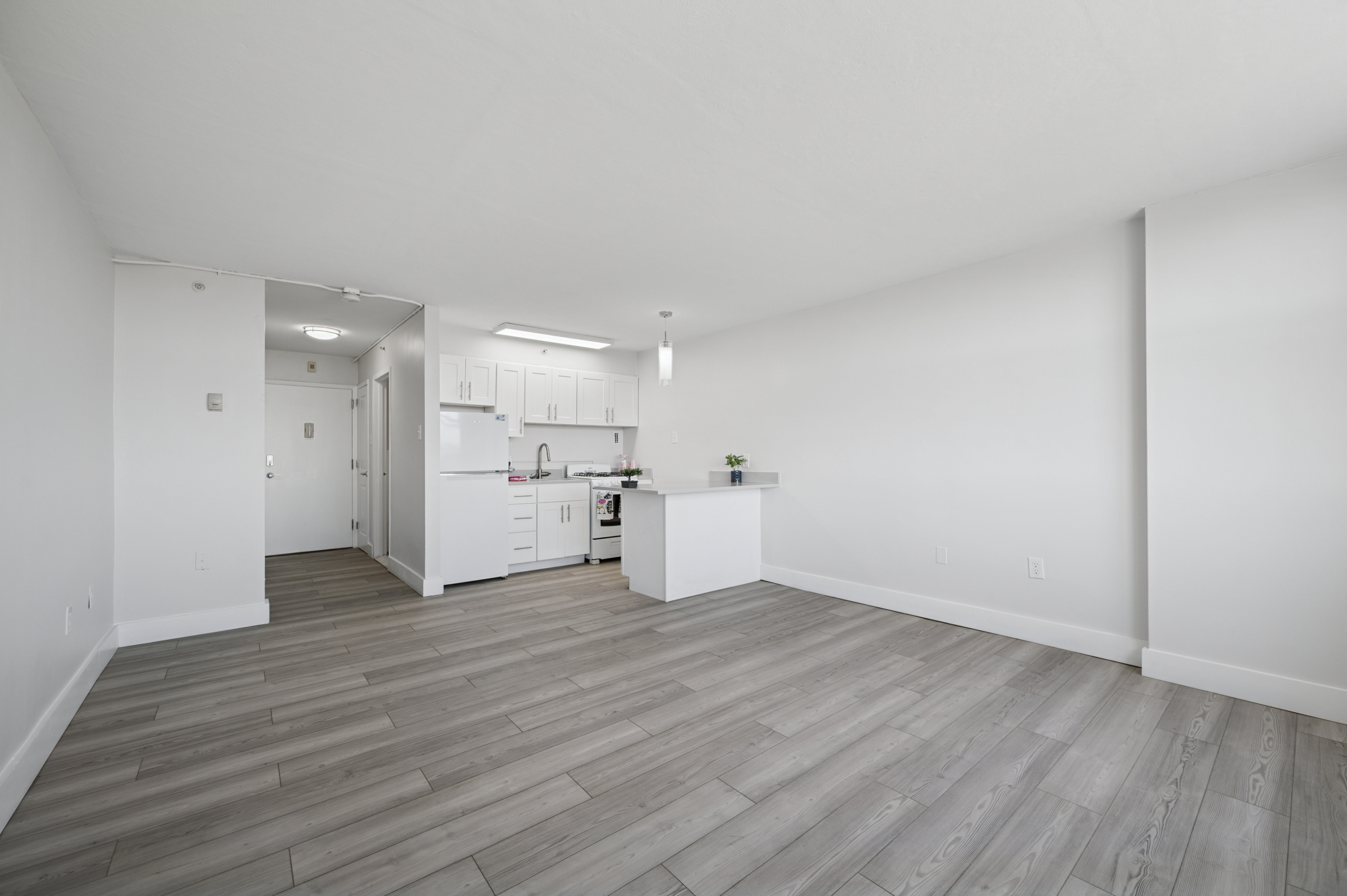 A kitchen with white cabinets and a wooden floor.