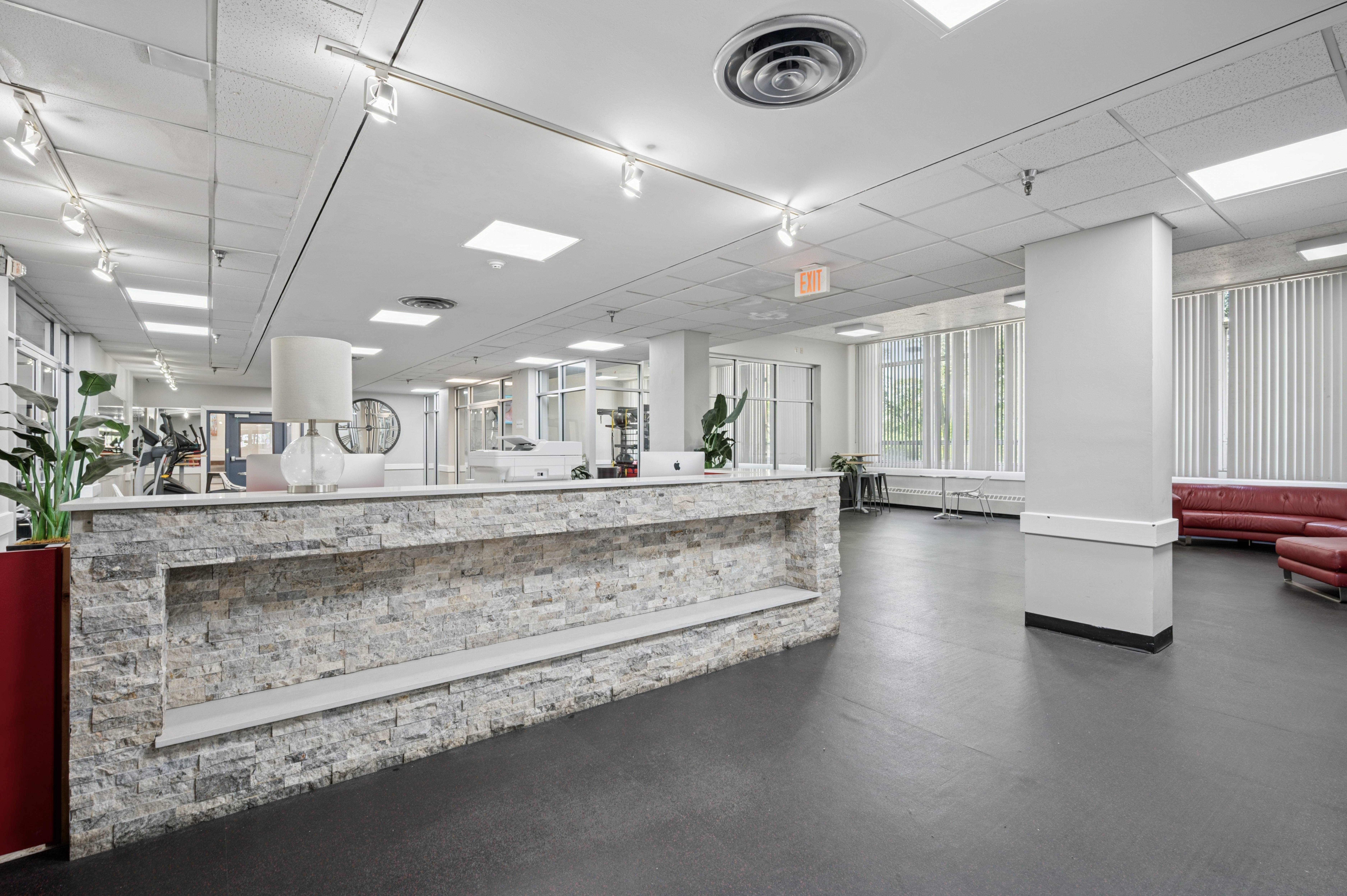 A reception area with a stone wall and a red couch.