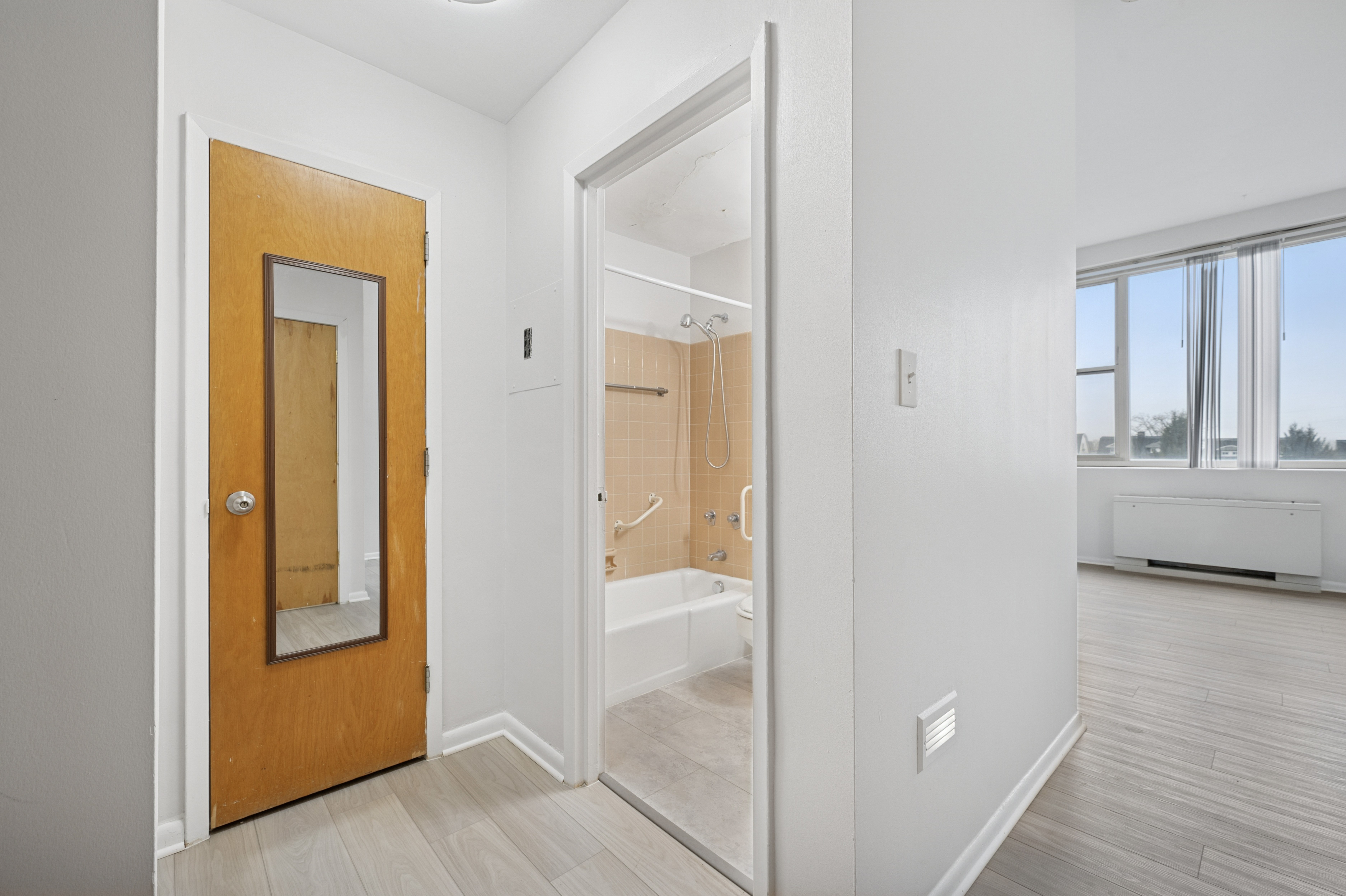 A room with a wooden door and a mirror on the wall.