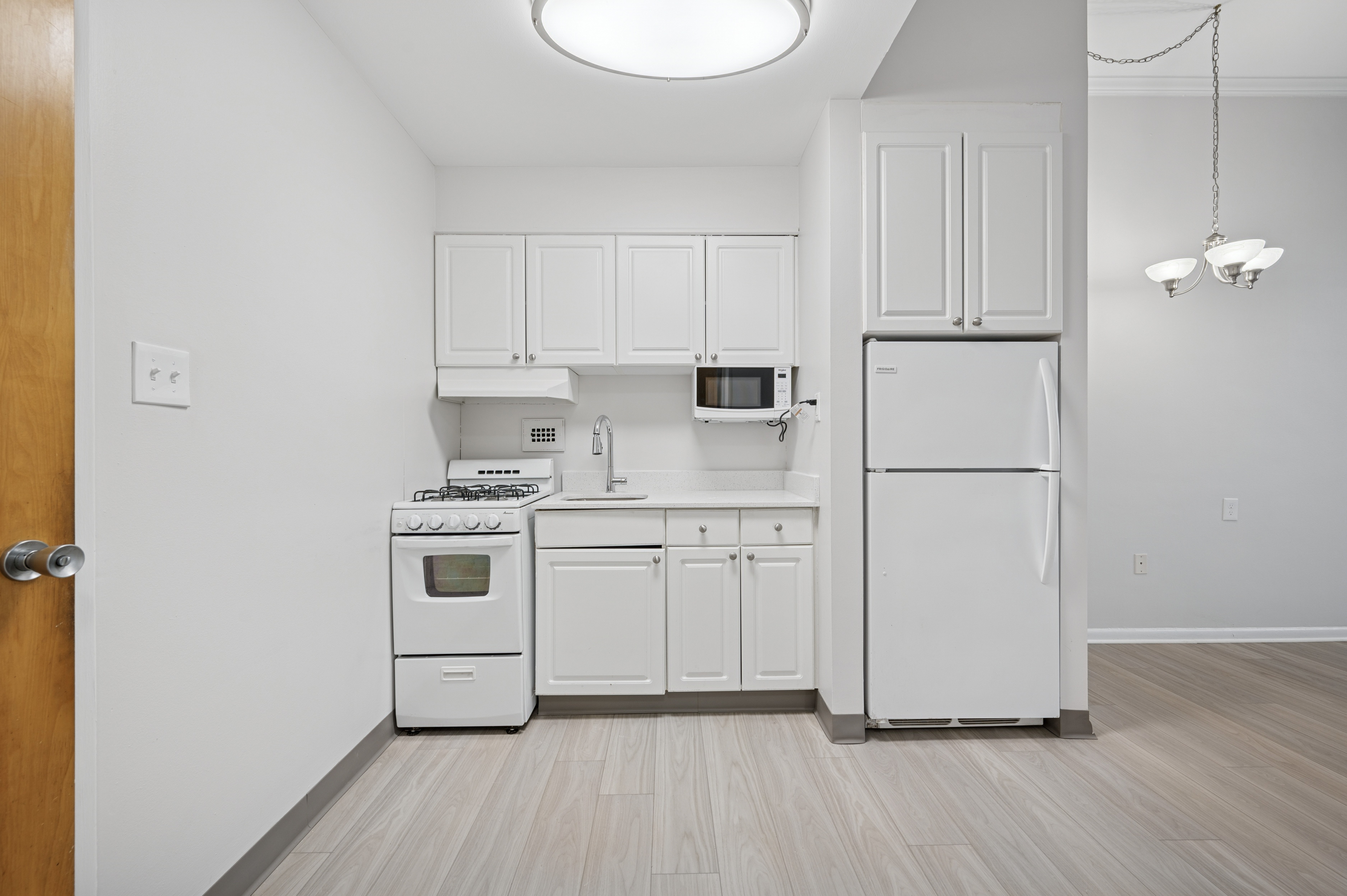 A kitchen with white appliances and cabinets.