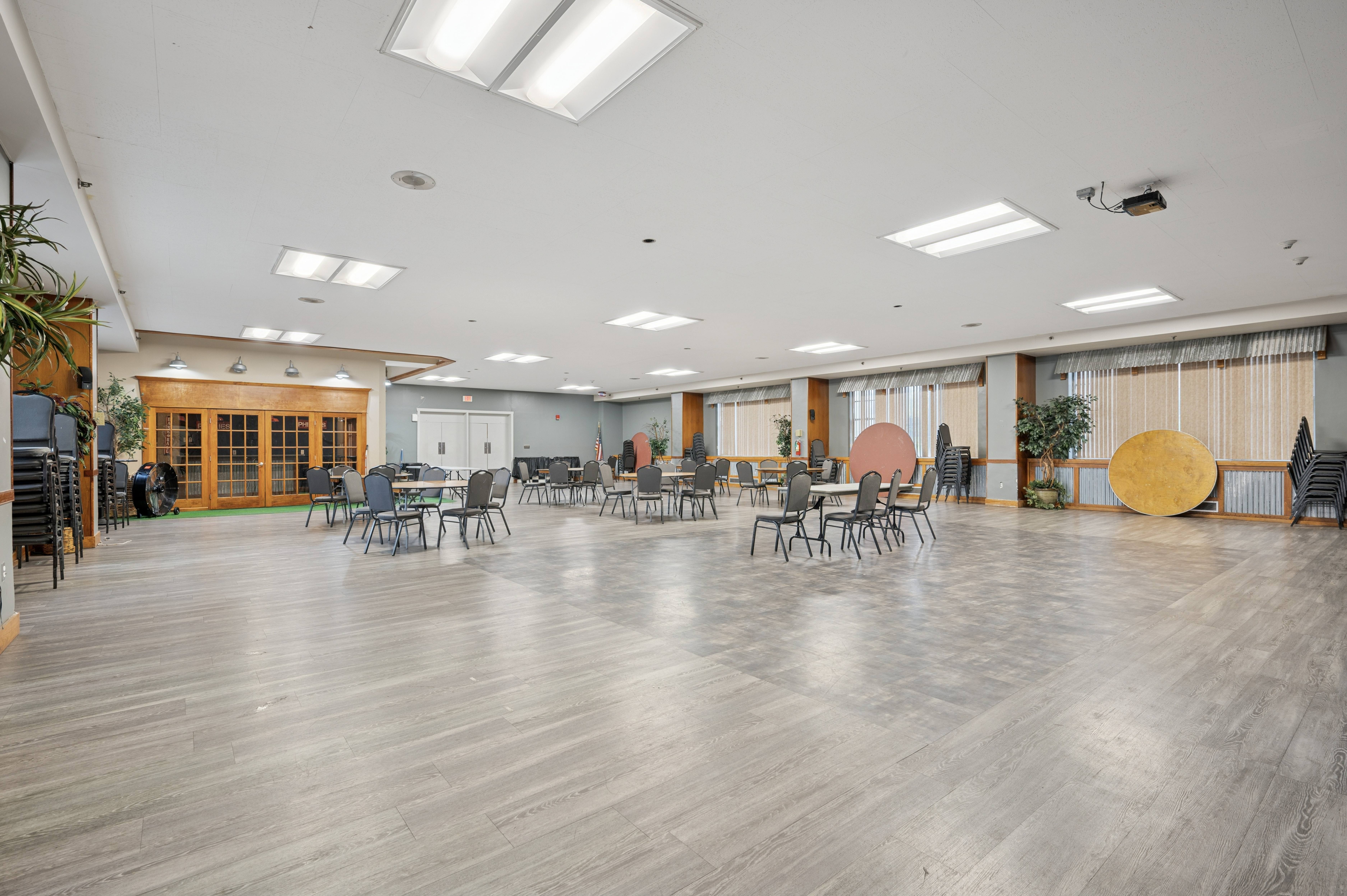 A spacious room with wooden floors and tables set up for an event.