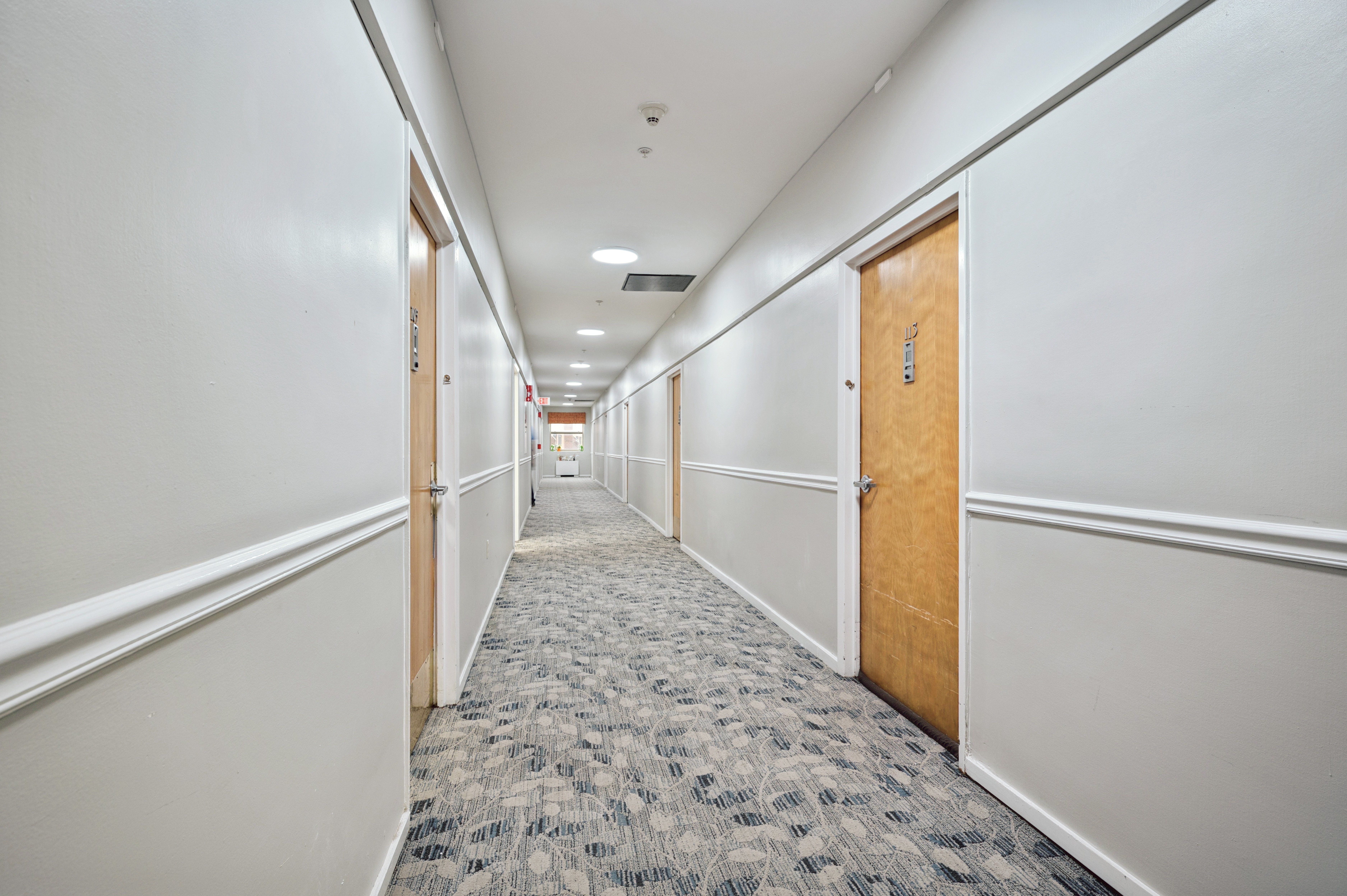 A long hallway with carpeted floors and white walls.