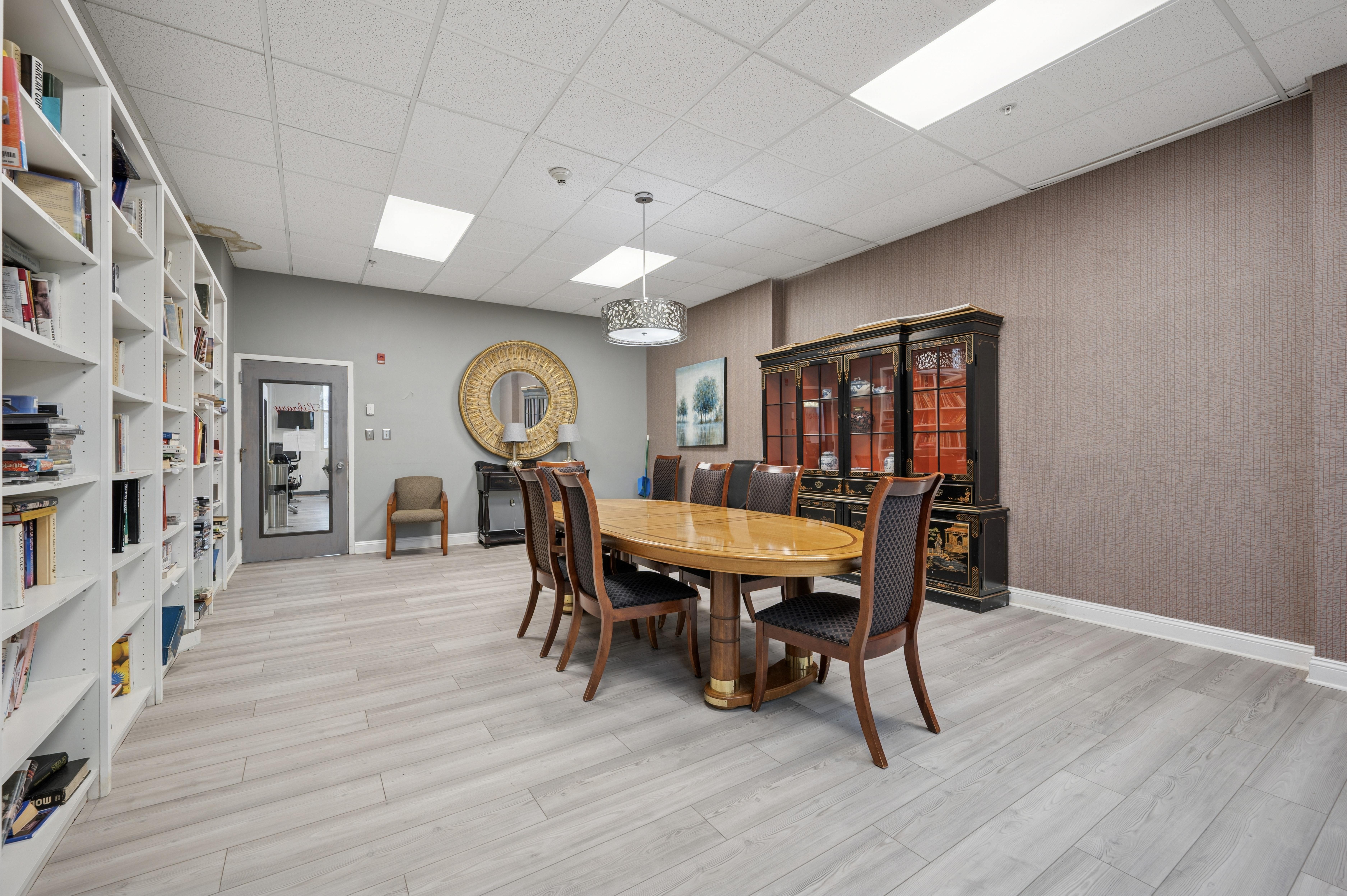 A room with a bookshelf, a table, and chairs.