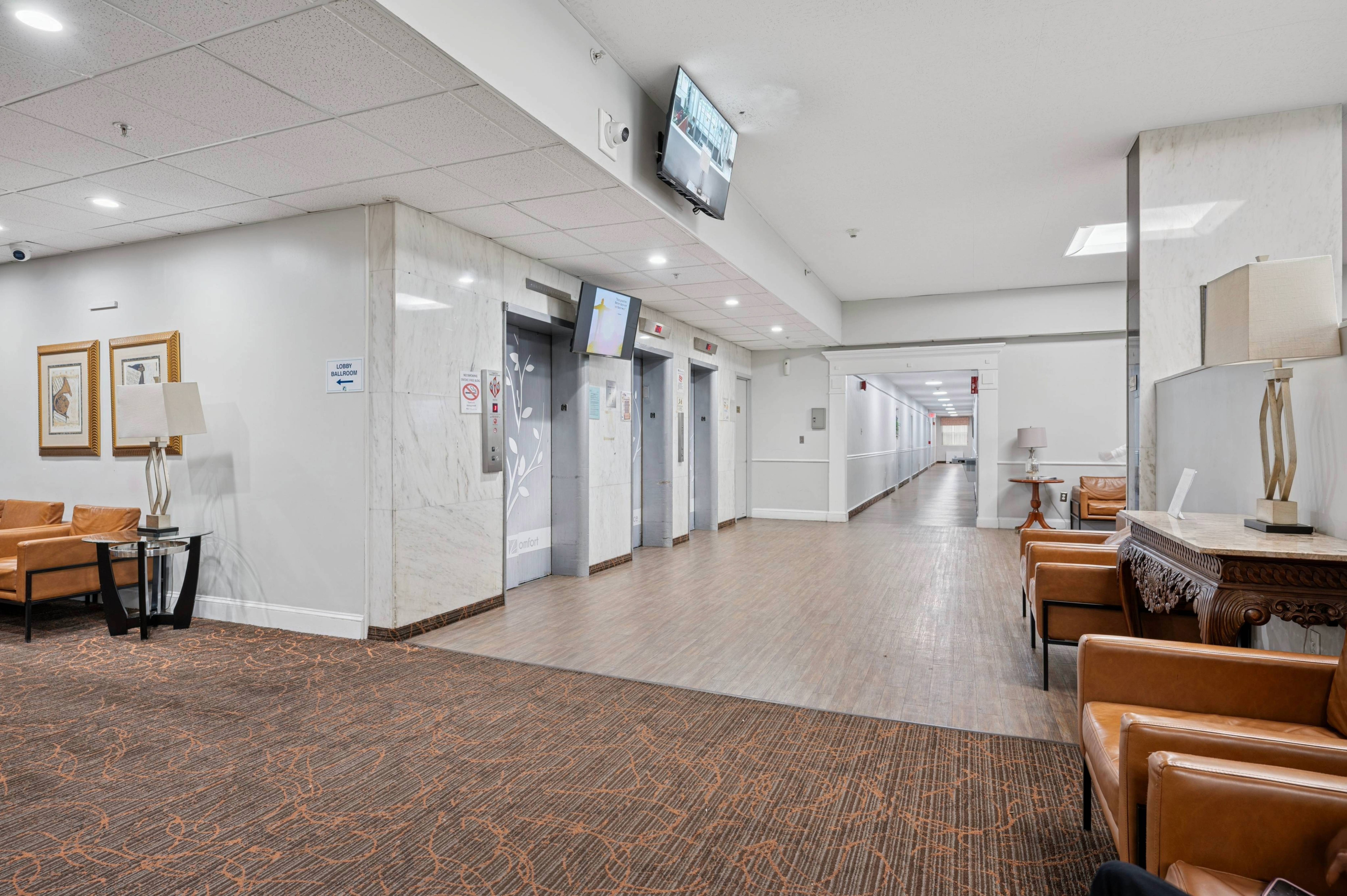 A long hallway with chairs and a television on the wall.