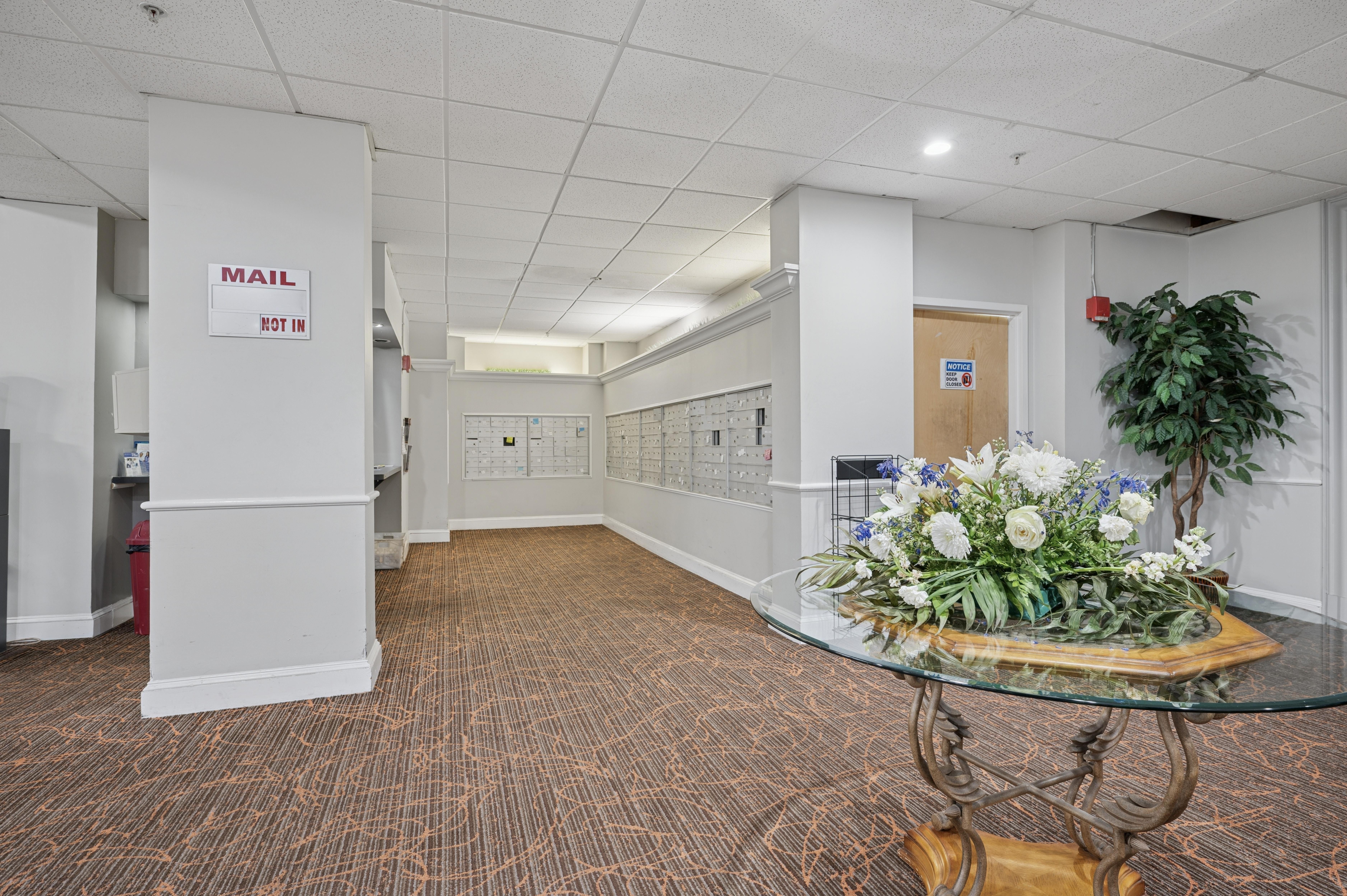 A reception area with a glass table and a plant.