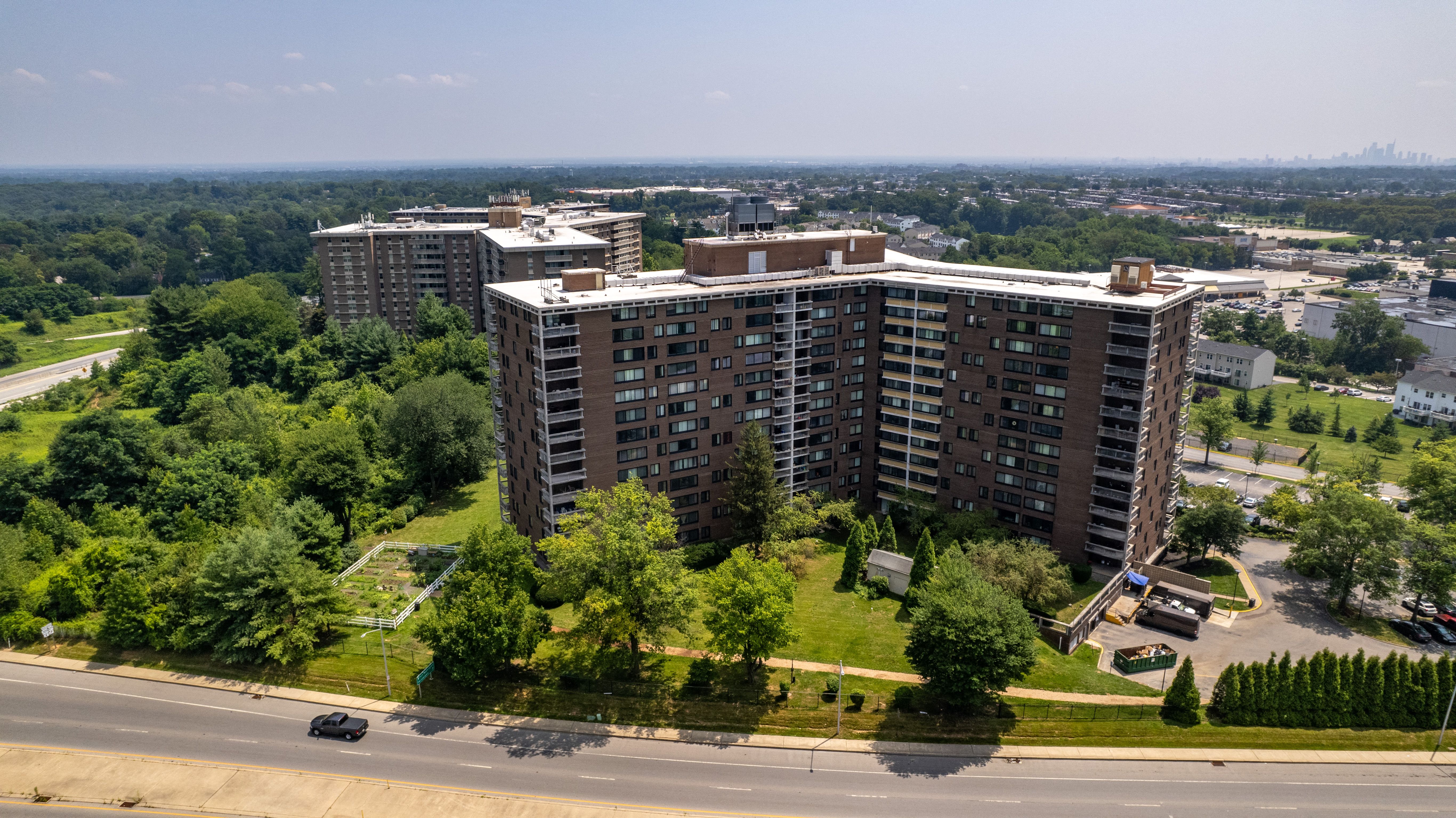 an aerial view of a large apartment building with trees in the foreground and a highway in the