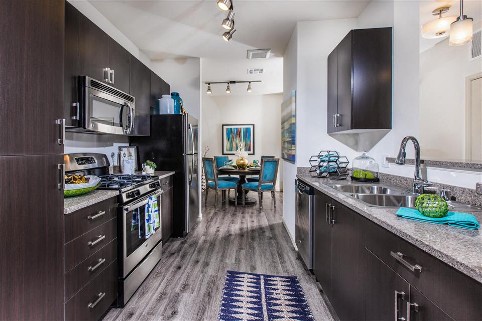 A sleek, modern kitchen leading into the dining room at the Venue Apartments in San Jose, California.