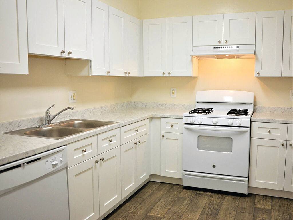 A white kitchen with hardwood floors at Parklane Apartments in Gaithersburg, Maryland.
