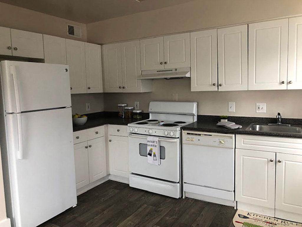 A white kitchen with dark counters at The Barrington Apartments in Silver Springs, Maryland.