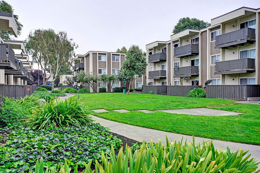 The building exterior and lawn with paths at the Turnleaf Apartment Homes in San Jose, California.