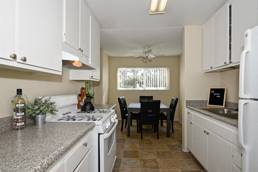 A white kitchen leading into the dining room at Canyon Rim Apartments in San Diego, California.