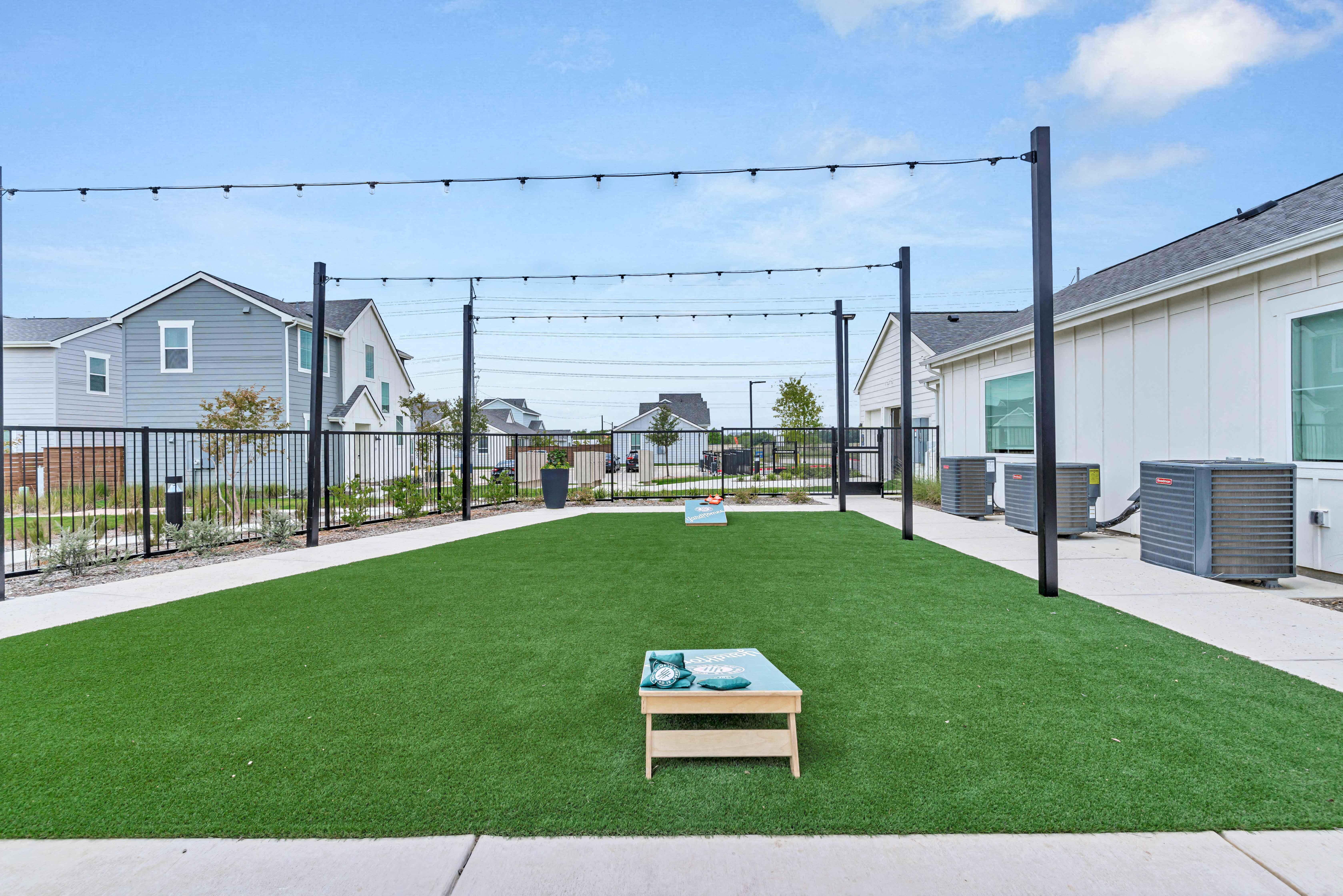 the yard is decorated with artificial grass and a fire pit