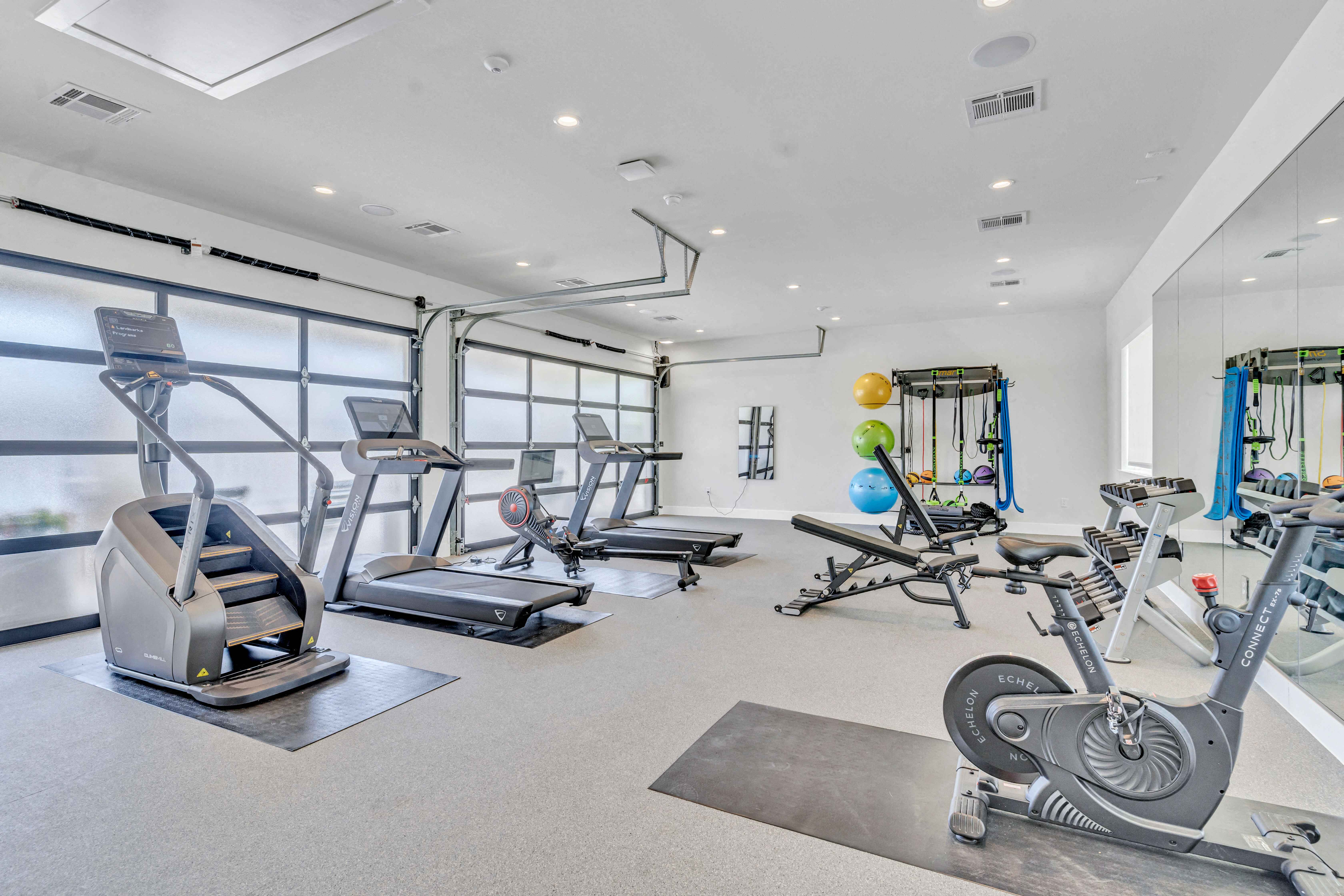 a gym with treadmills and weights in a room with windows