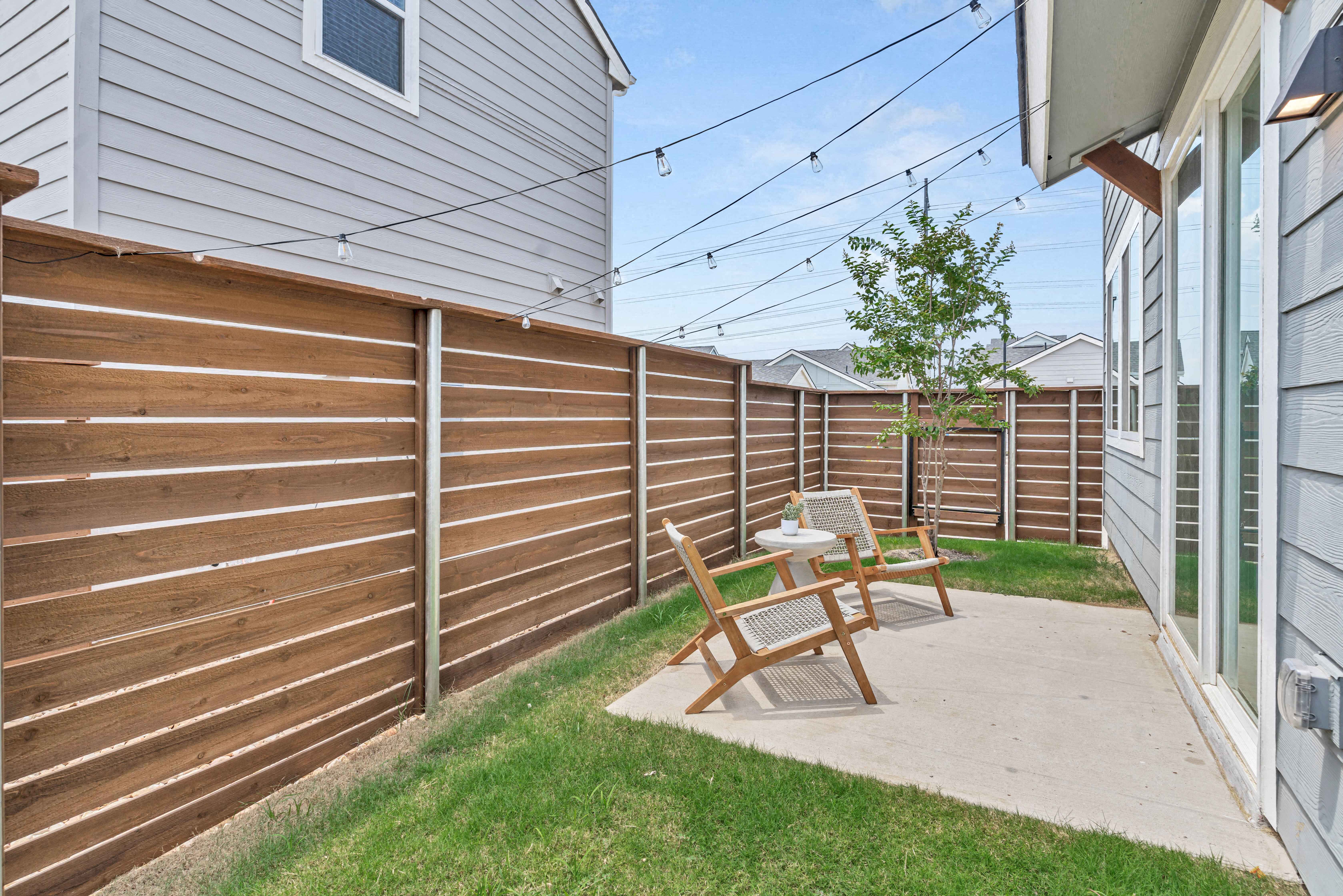 a patio with a wooden privacy fence and a table and chairs