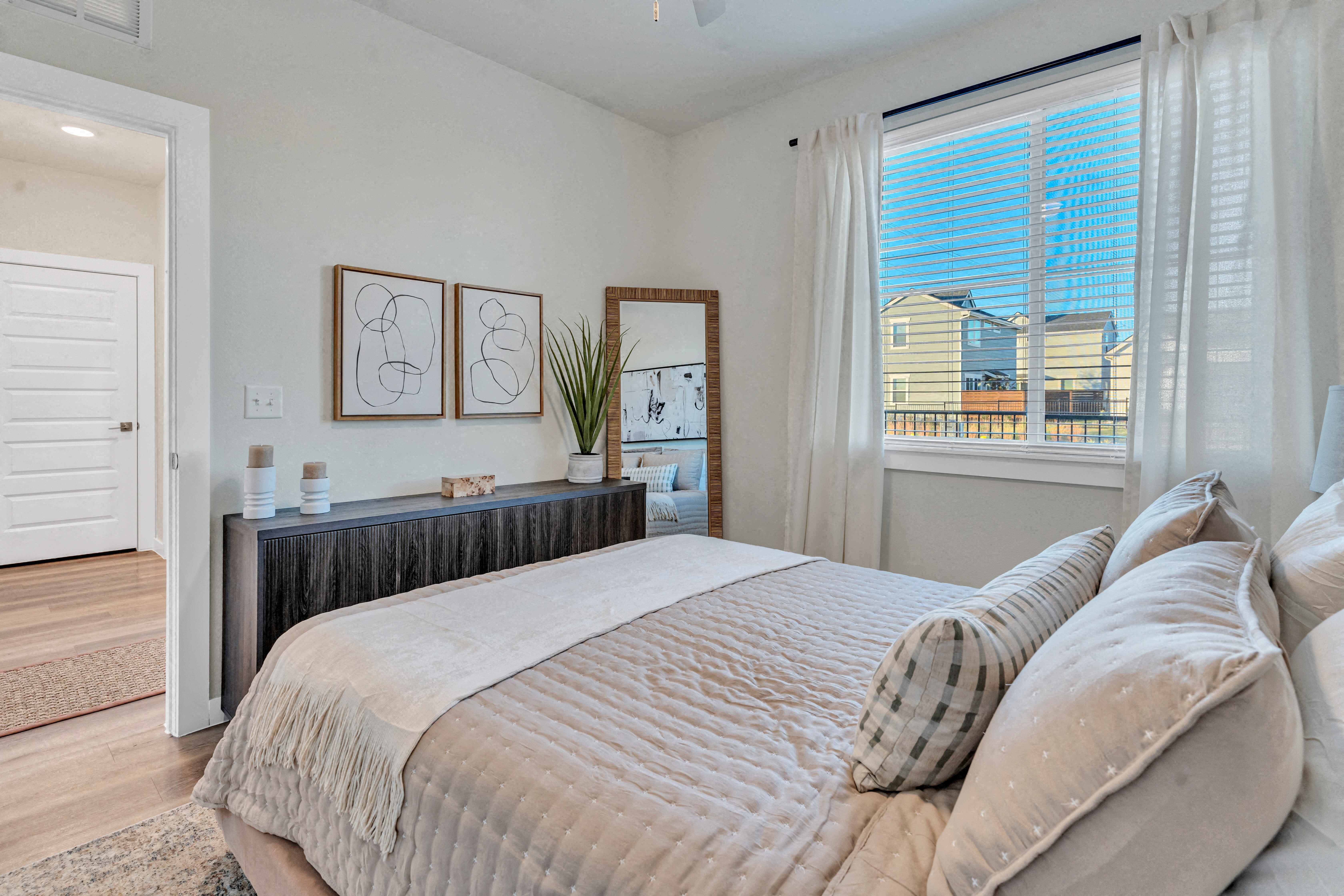 A bedroom with a large bed and a window overlooking a building.