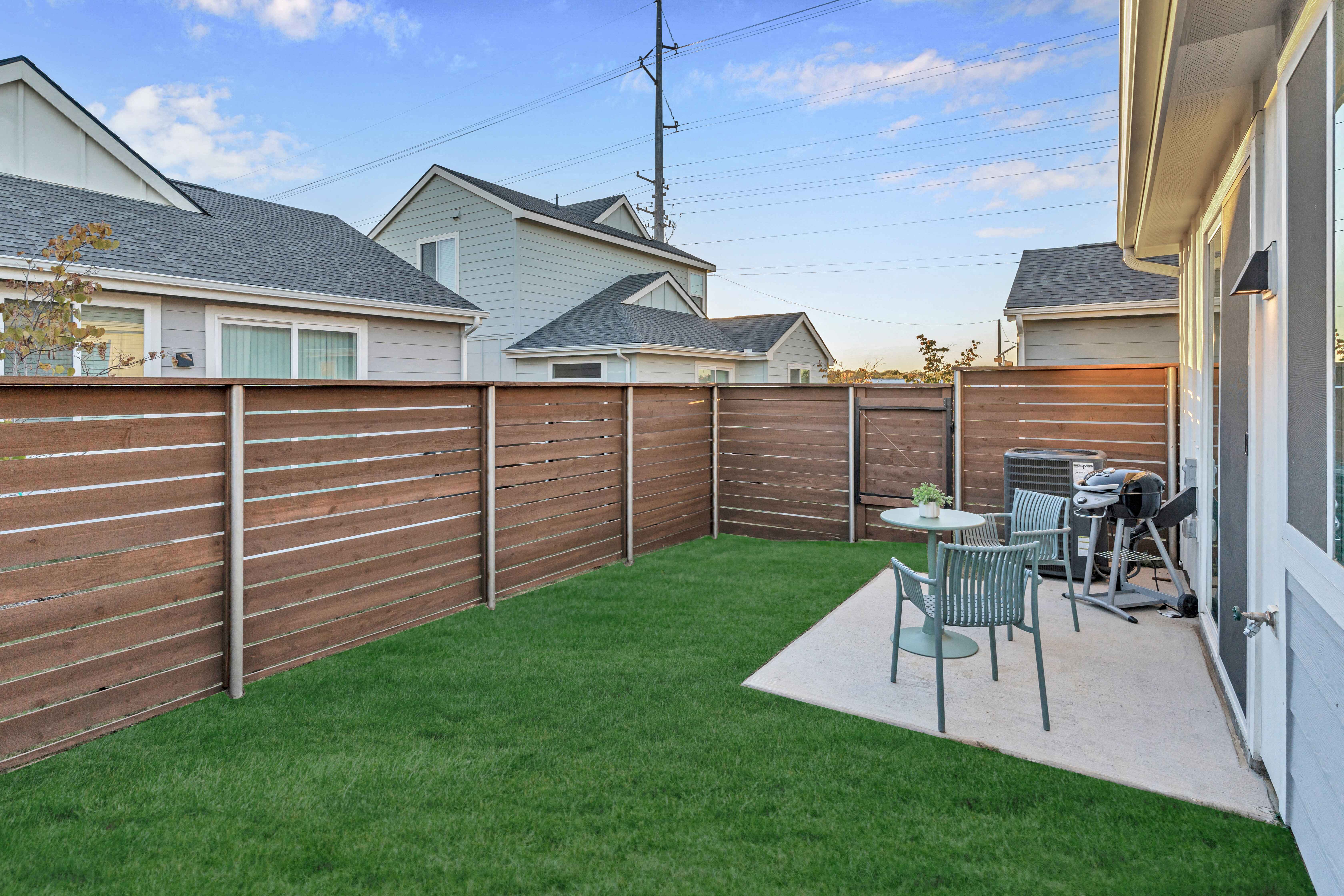 A backyard with a wooden fence and a small table and chairs.