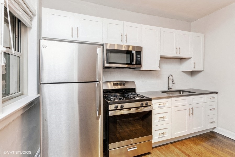 Stainless steel appliances, stone countertops, and white cabinets in renovated kitchens  at Ivy Promenade | Hyde Park Chicago Apartments near UChicago | 5447 S Woodlawn Ave