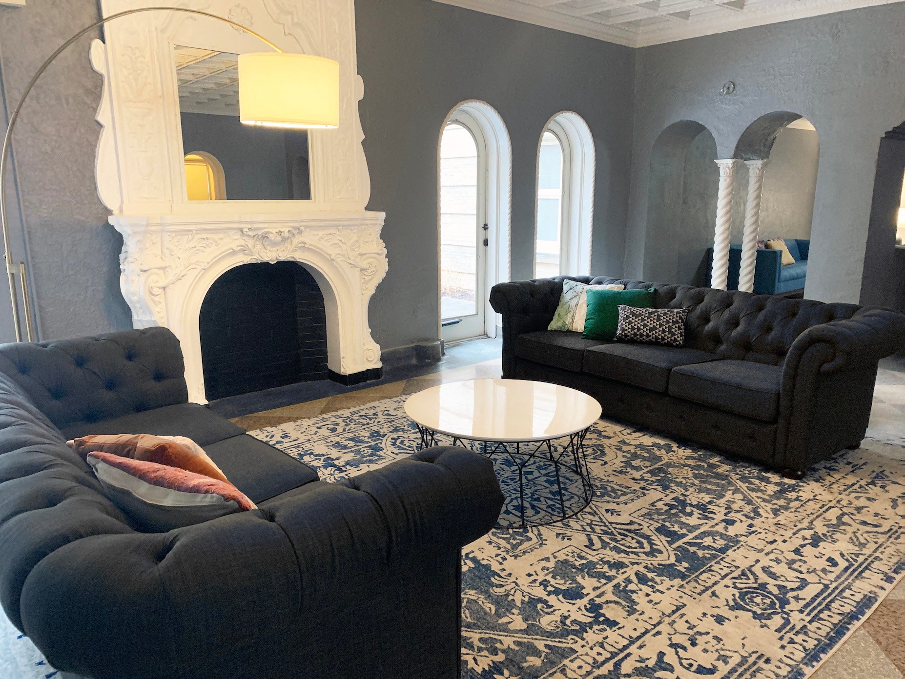 Ivy Villas lobby outfitted with original decorative fireplace, two rolled-arm sofas, chic decor, and arched windows soaking the room with sunlight from the private courtyard. 5514 S Blackstone Ave
