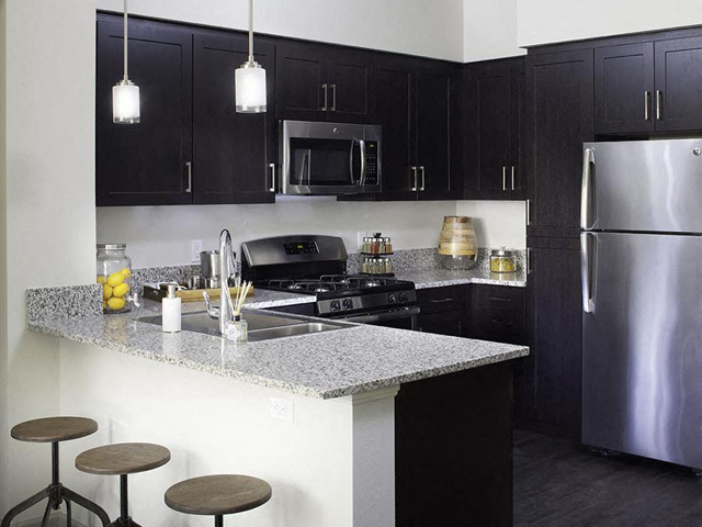 A modern kitchen with dark cabinetry at the Skye Apartments in Vista, California.